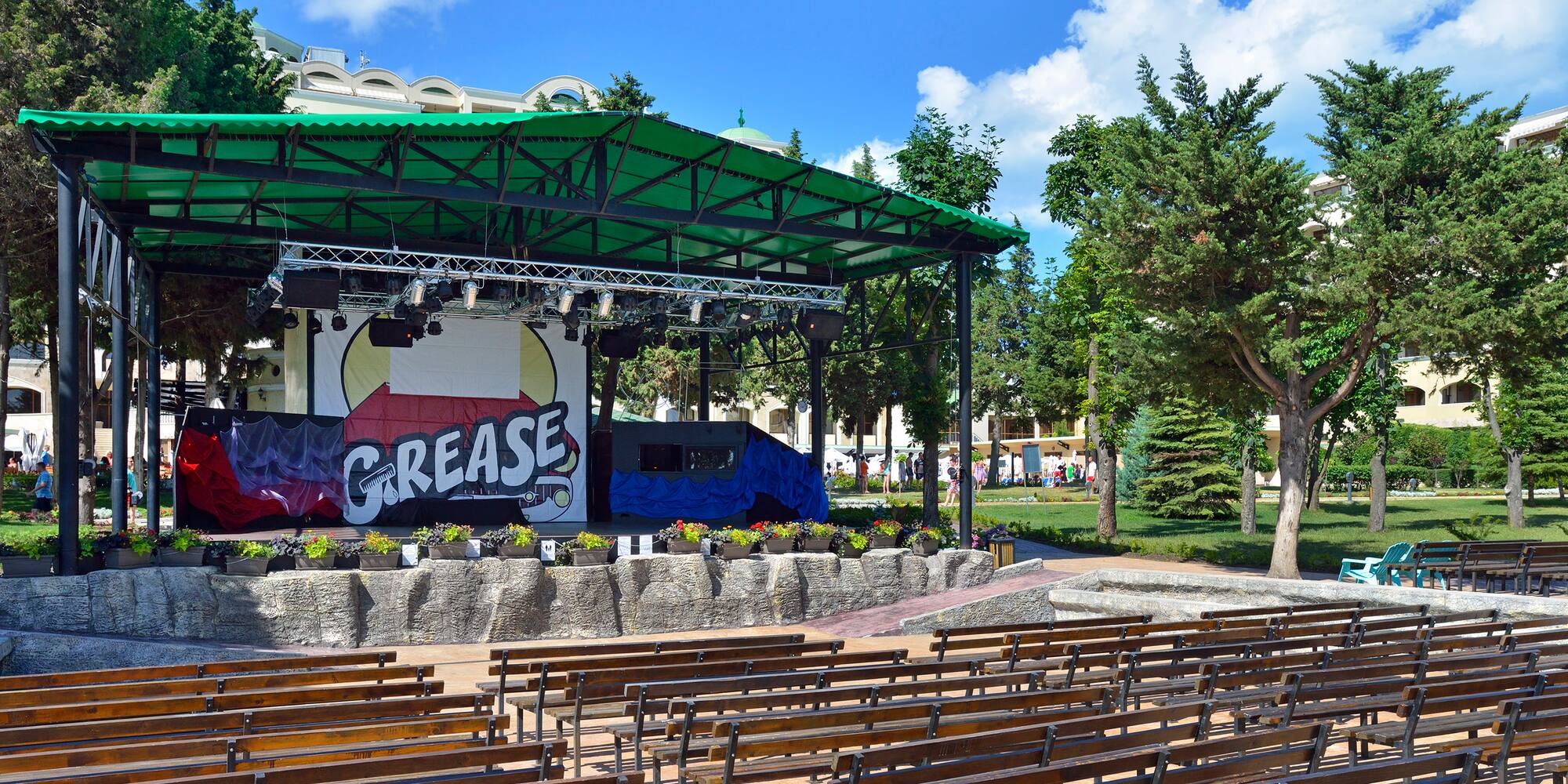 a stage with a green roof and benches in front of it