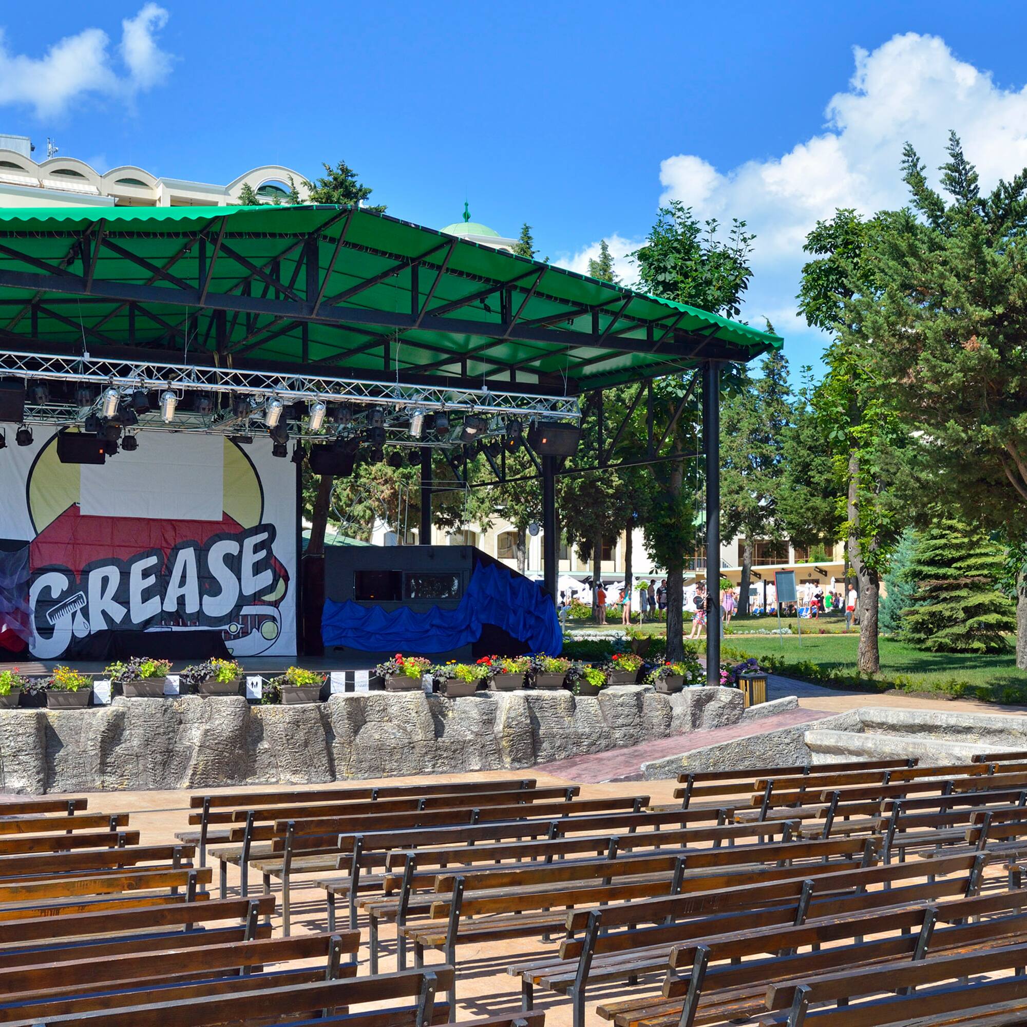a stage with a green roof and benches in front of it