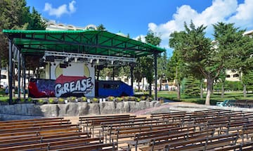 a stage with a green roof and benches in front of it