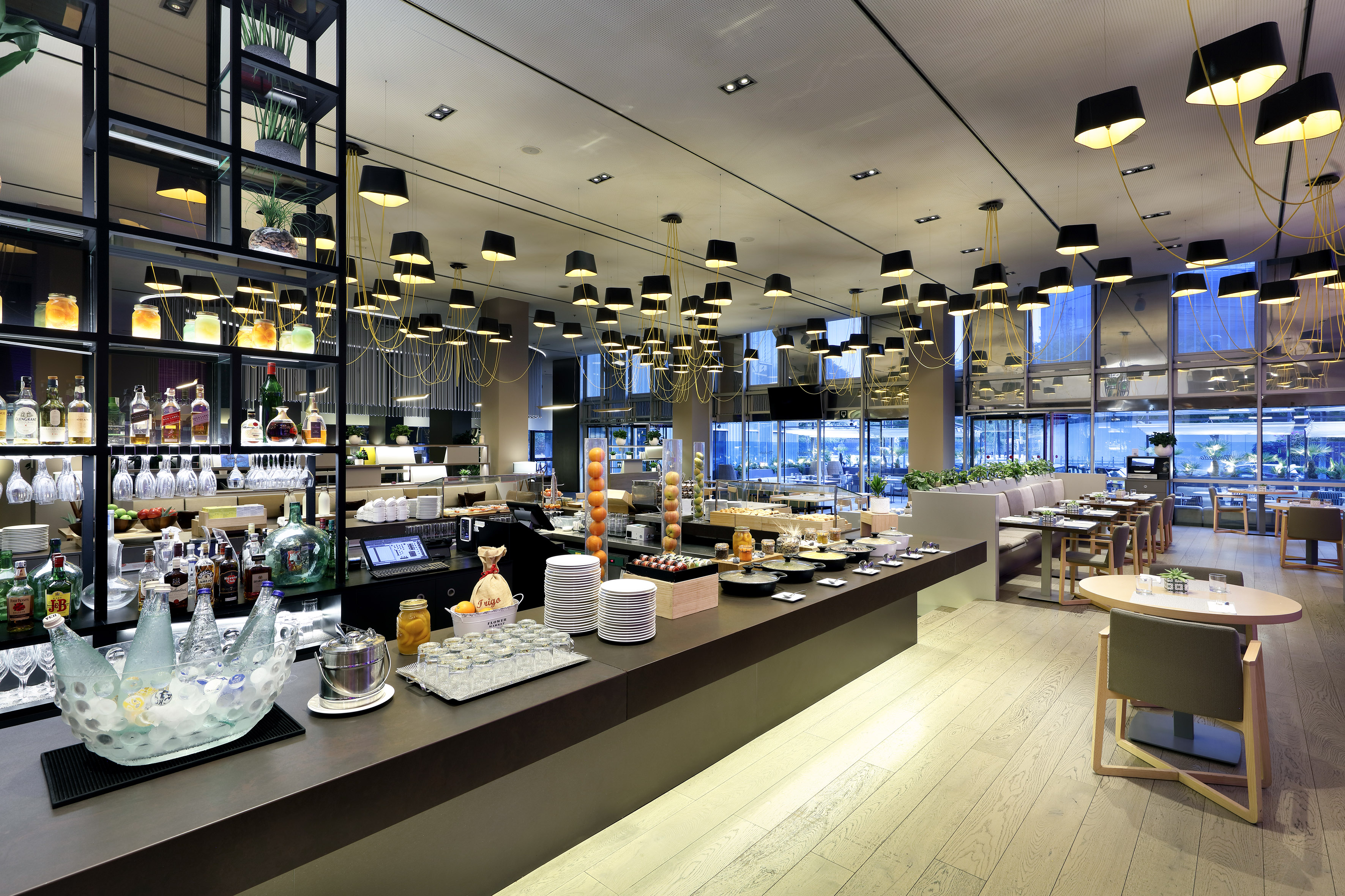 Modern hotel restaurant buffet with food, bar, and stylish pendant lighting.