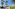 White hotel buildings, palm trees, stone path, and desert landscape.