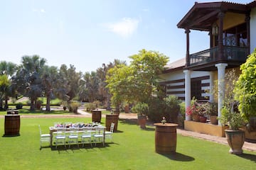 a white chairs and tables in a yard with trees and a building