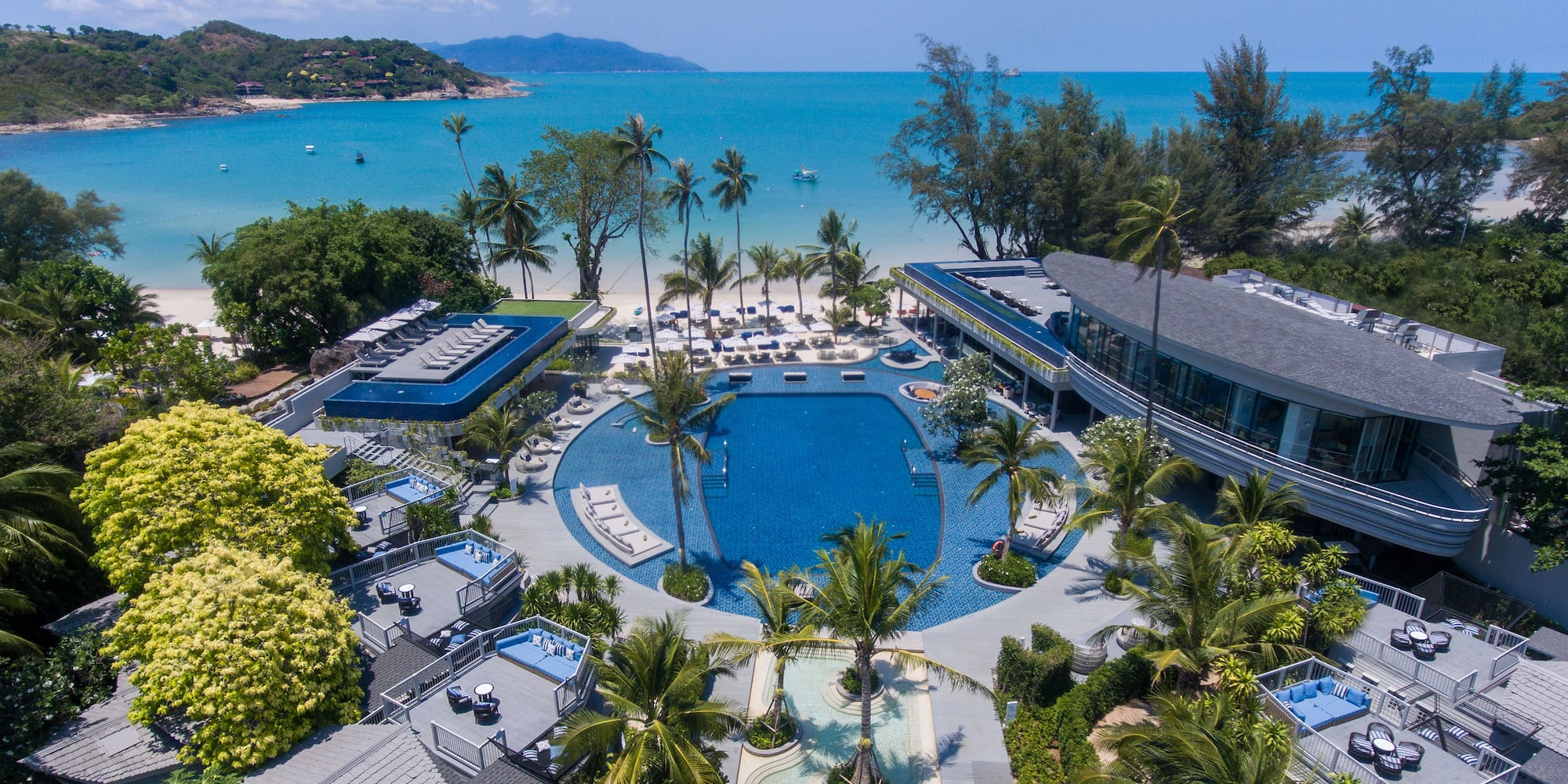 Luxury tropical beach resort with pools, palm trees, and turquoise ocean.