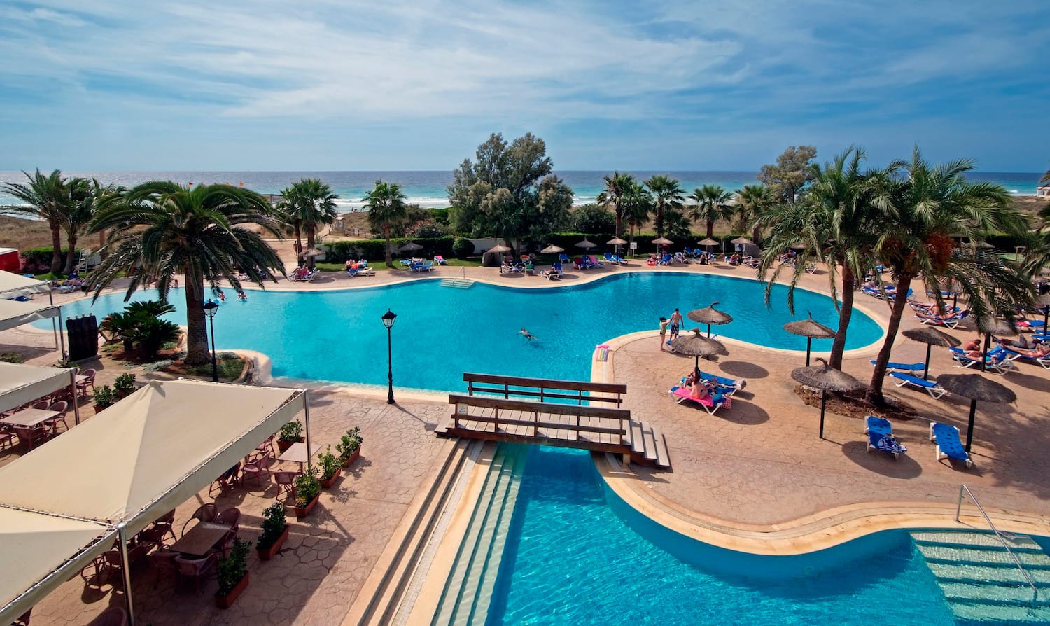 a swimming pool with people and umbrellas