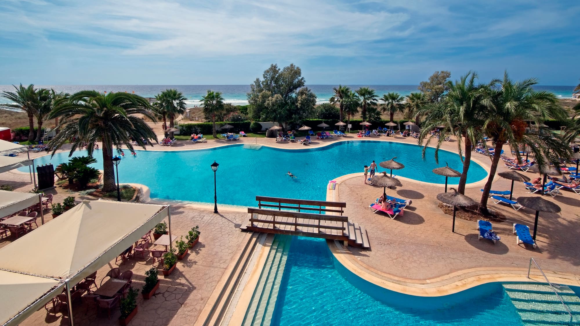 a swimming pool with people and umbrellas