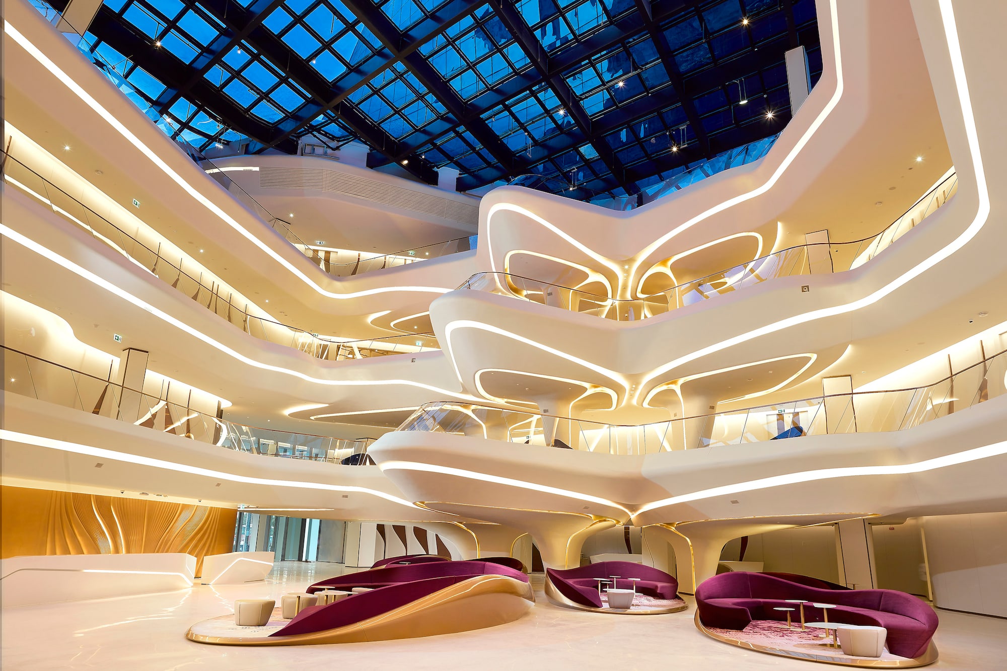Modern multi-level atrium with curved architecture, integrated LED lighting, and glass roof.