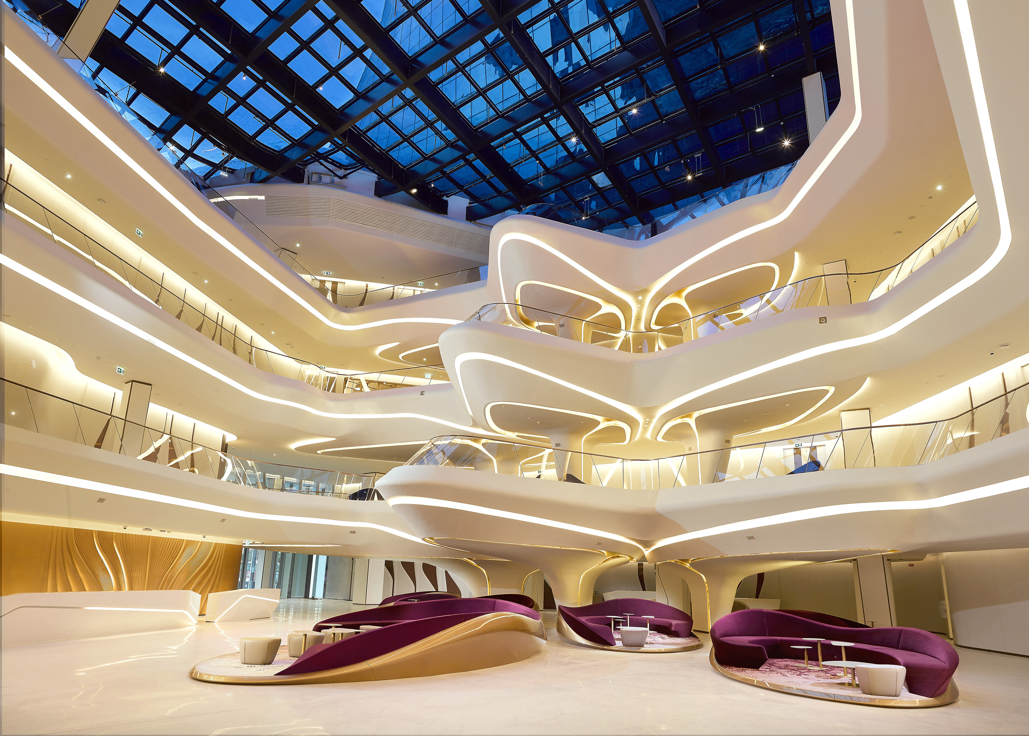 Modern multi-level atrium with curved architecture, integrated LED lighting, and glass roof.