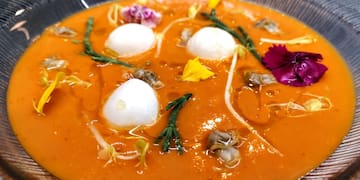 a bowl of soup with flowers and eggs