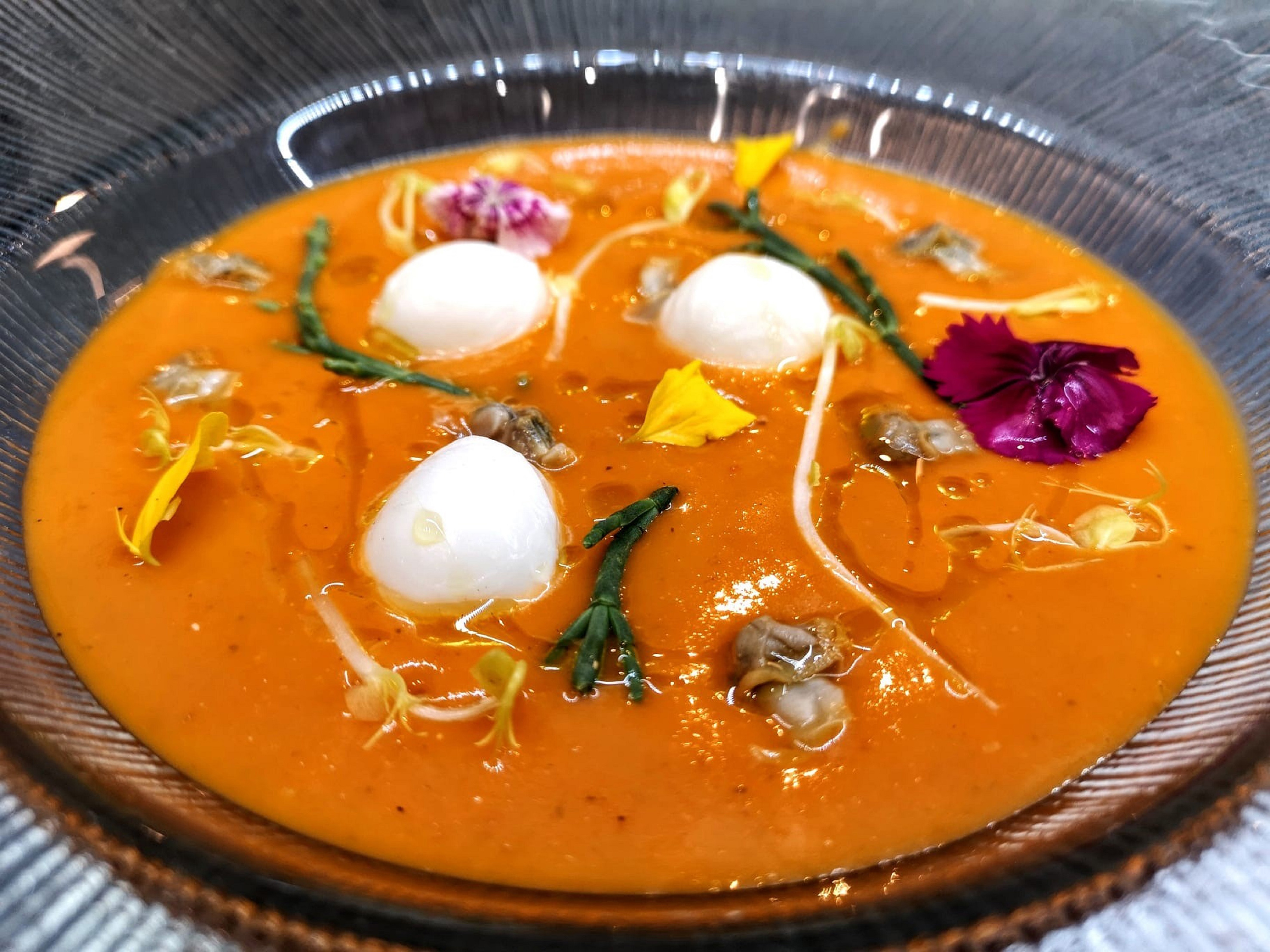 Vibrant gourmet gazpacho with quail eggs, clams, samphire, and edible flowers.