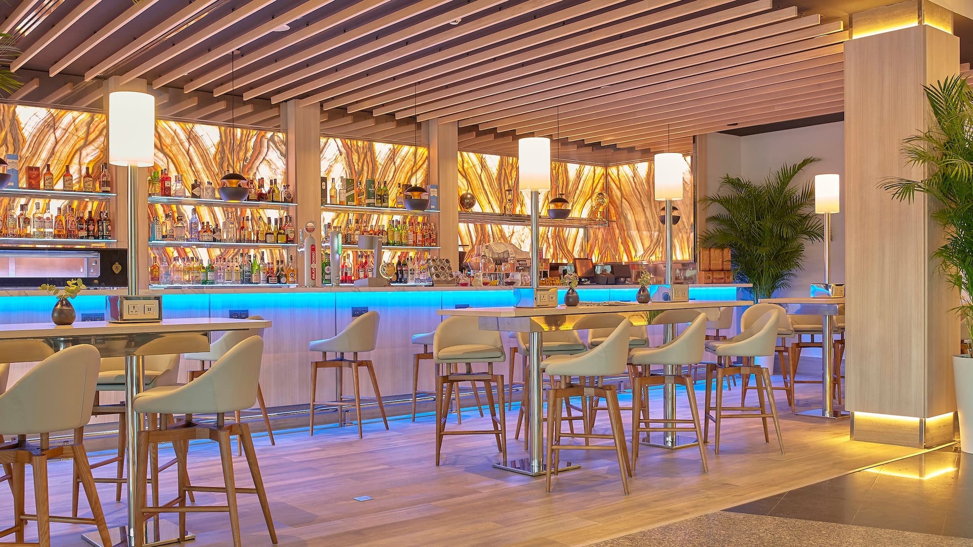 a bar with a row of chairs and a shelf with bottles