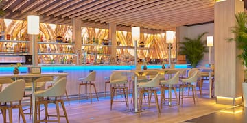 a bar with a row of chairs and a shelf with bottles