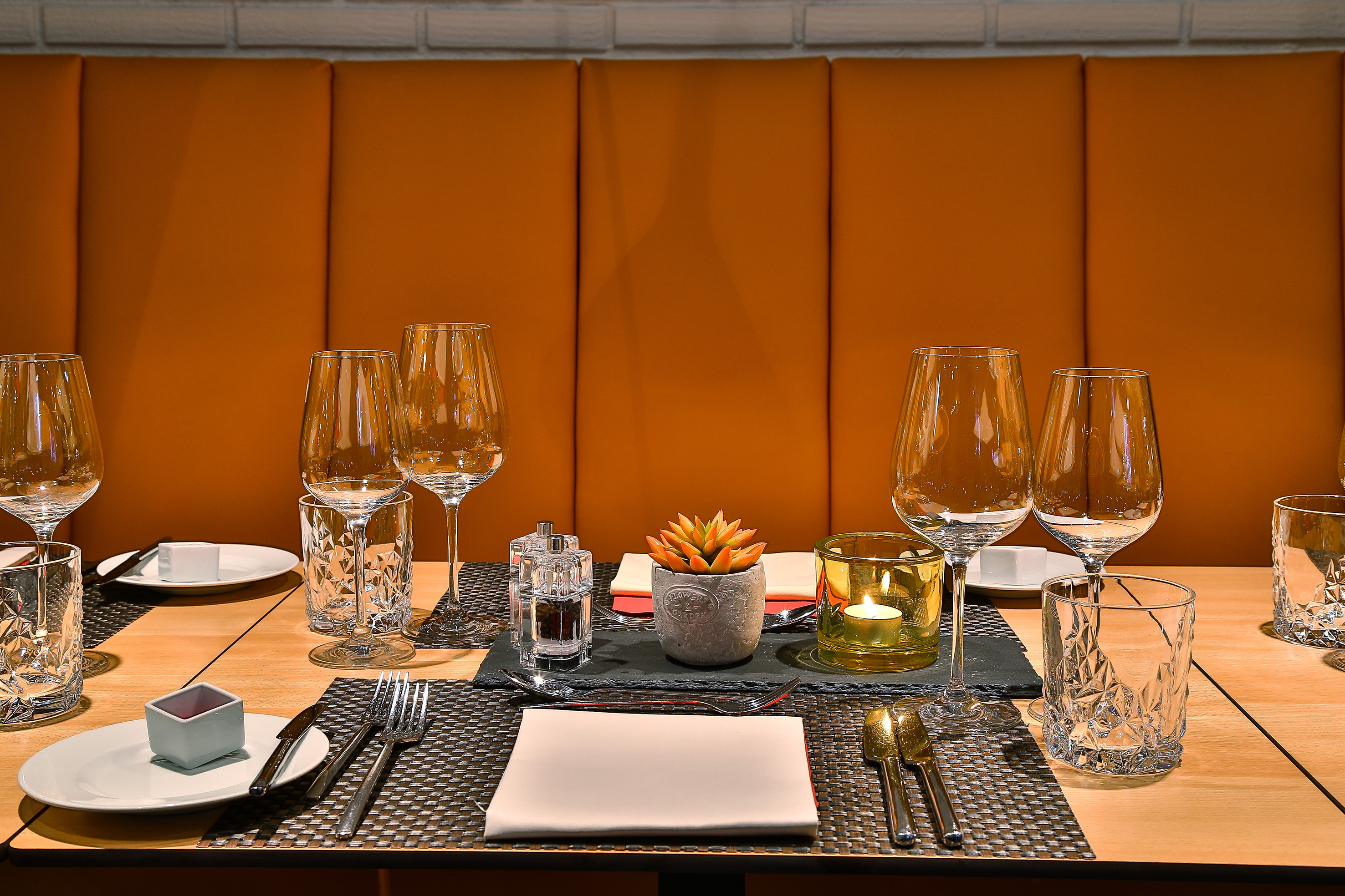 Elegant restaurant table setup with wine glasses, silverware, and glowing candle.