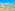 Colorful coastal town with white buildings, palm trees, sandy beach, and blue ocean.