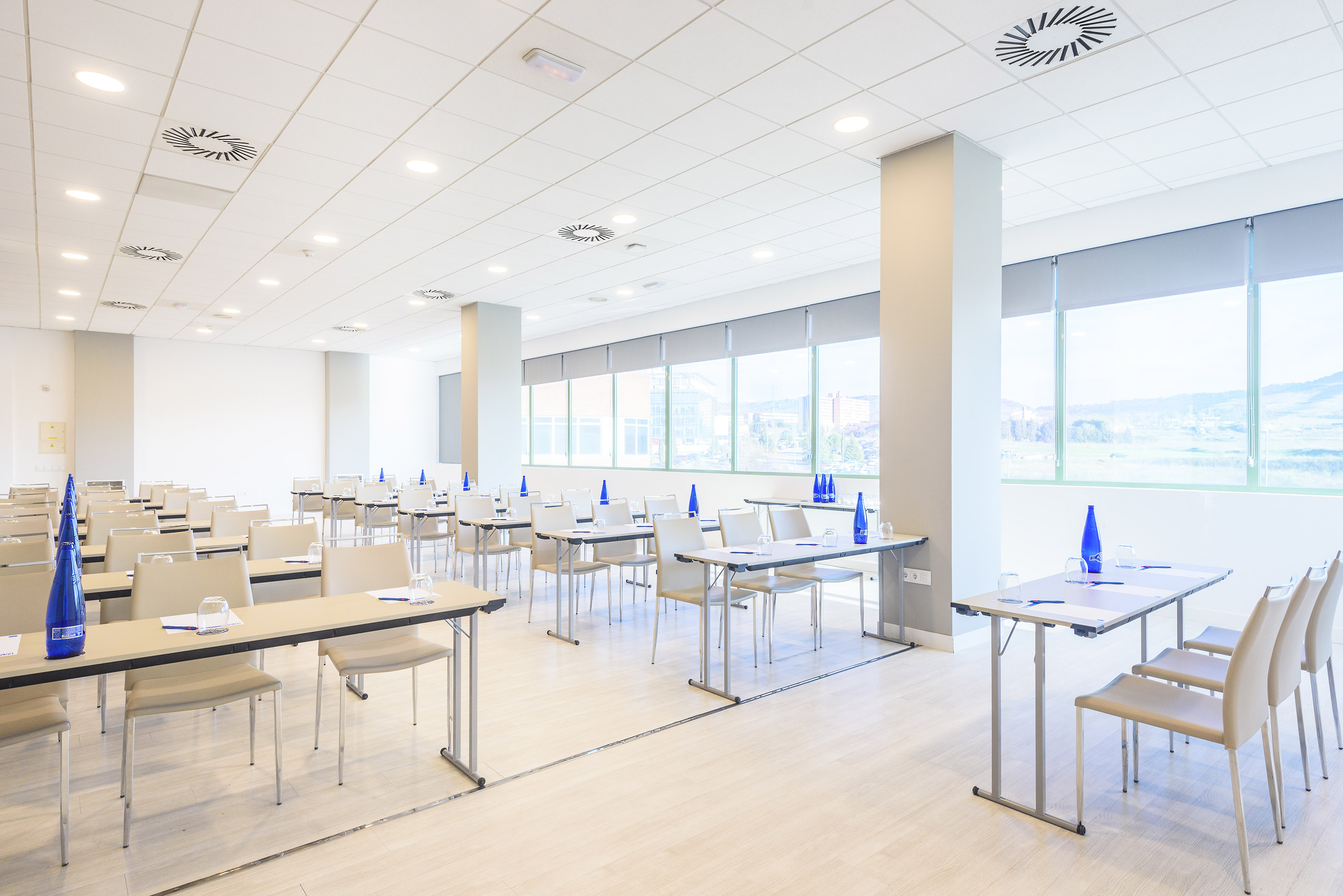 Modern conference room with tables, chairs, and bright windows.