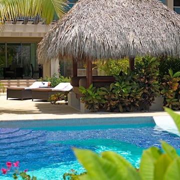 a pool with a straw umbrella and lounge chairs