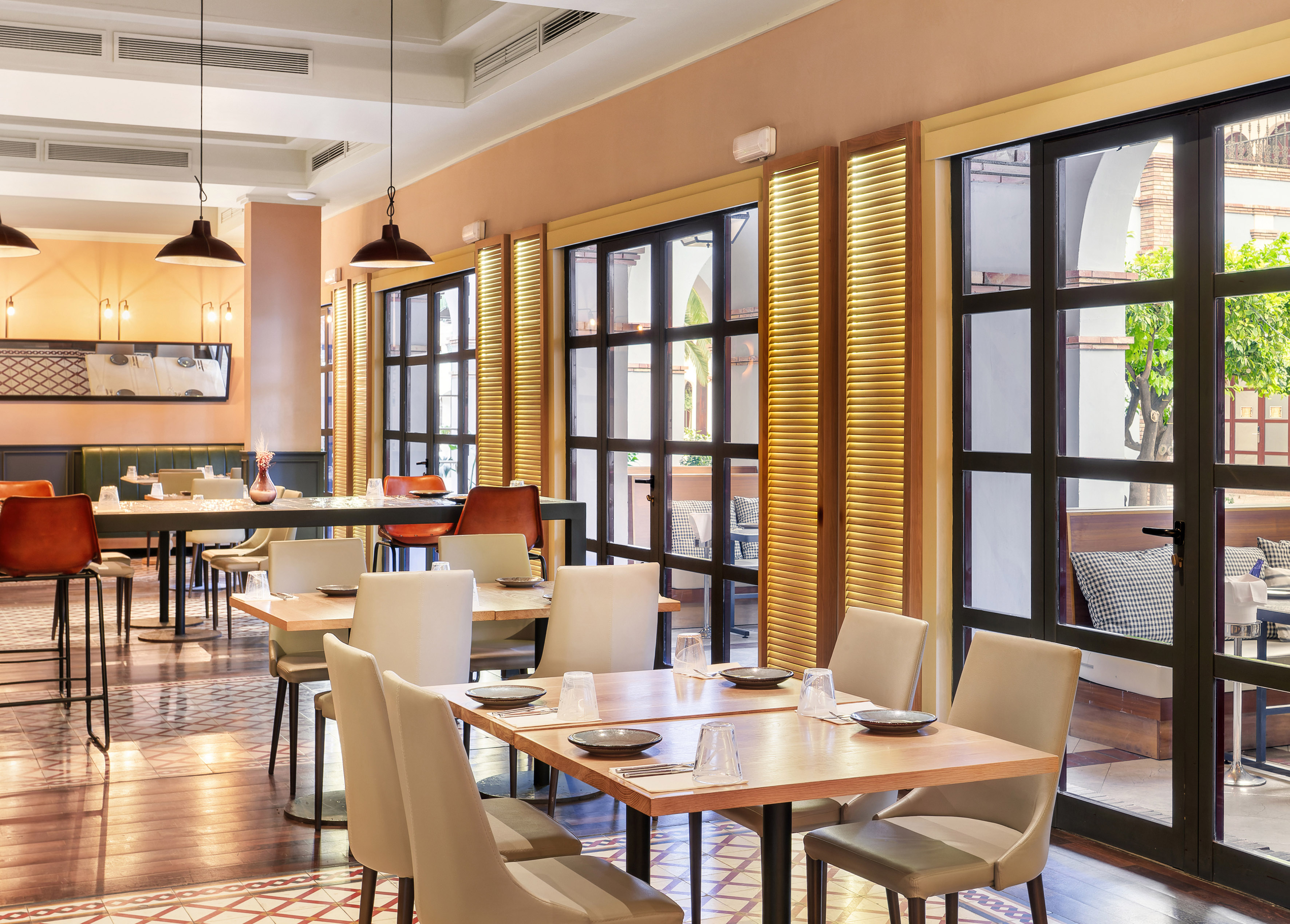 Modern restaurant dining area with set tables, large windows, and patio view.