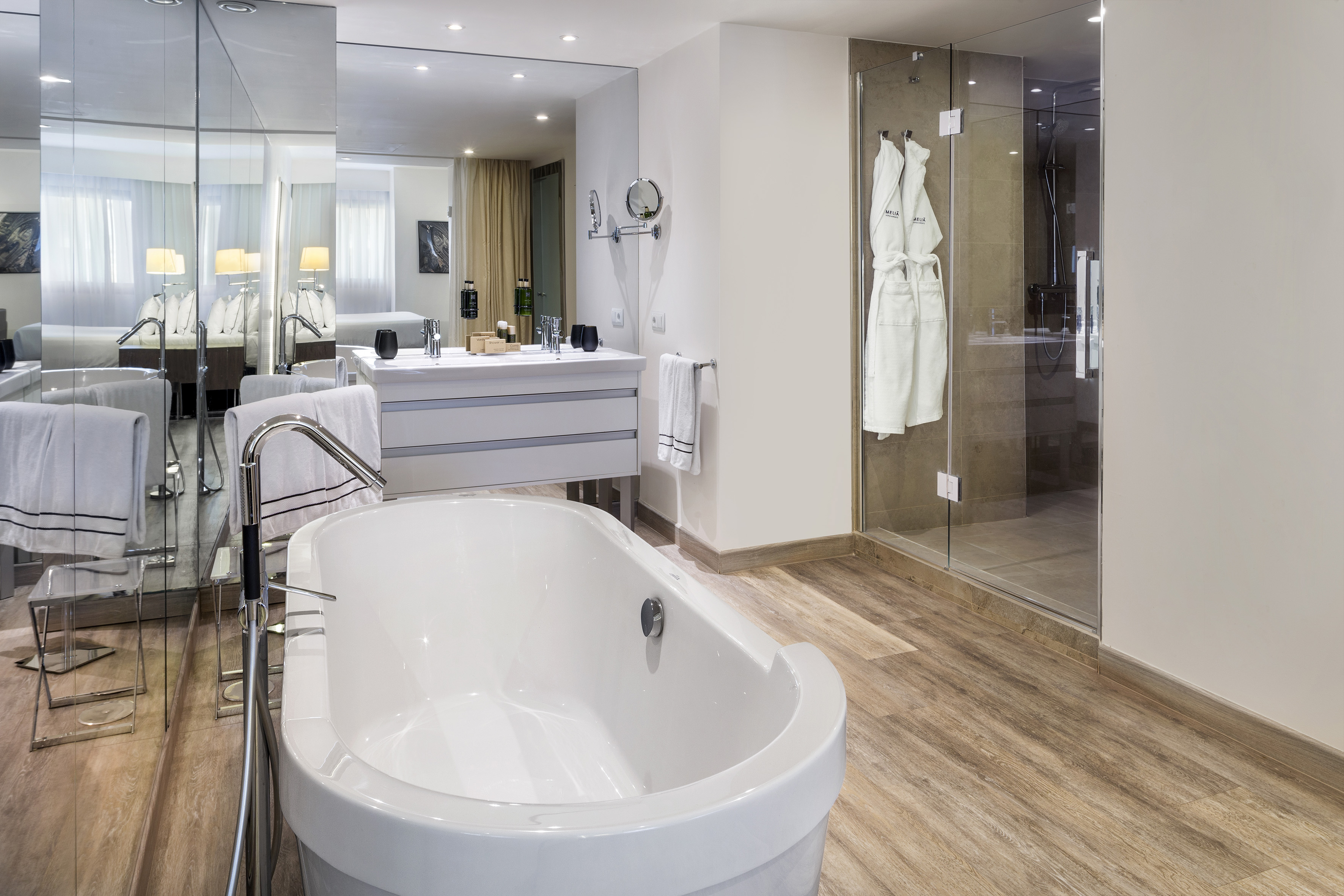 Modern hotel bathroom with freestanding tub, double vanity, and glass shower.