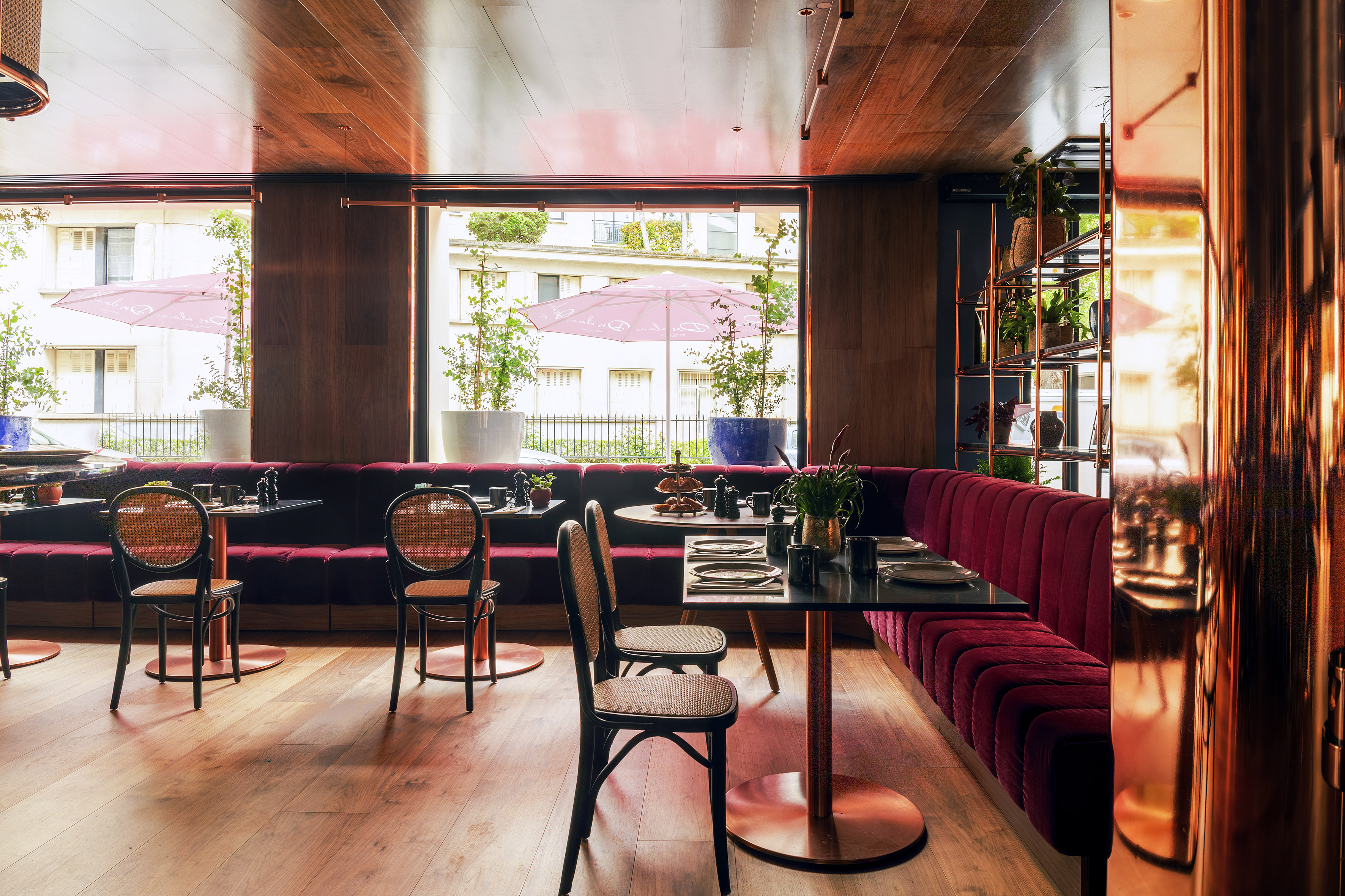 Restaurant interior: red velvet banquettes, wood paneling, black tables, and city view.