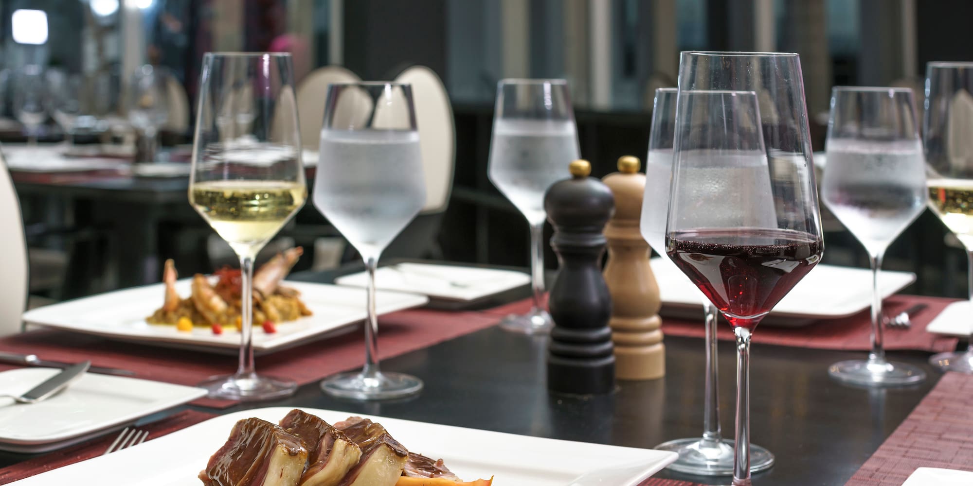 a table with plates of food and wine glasses