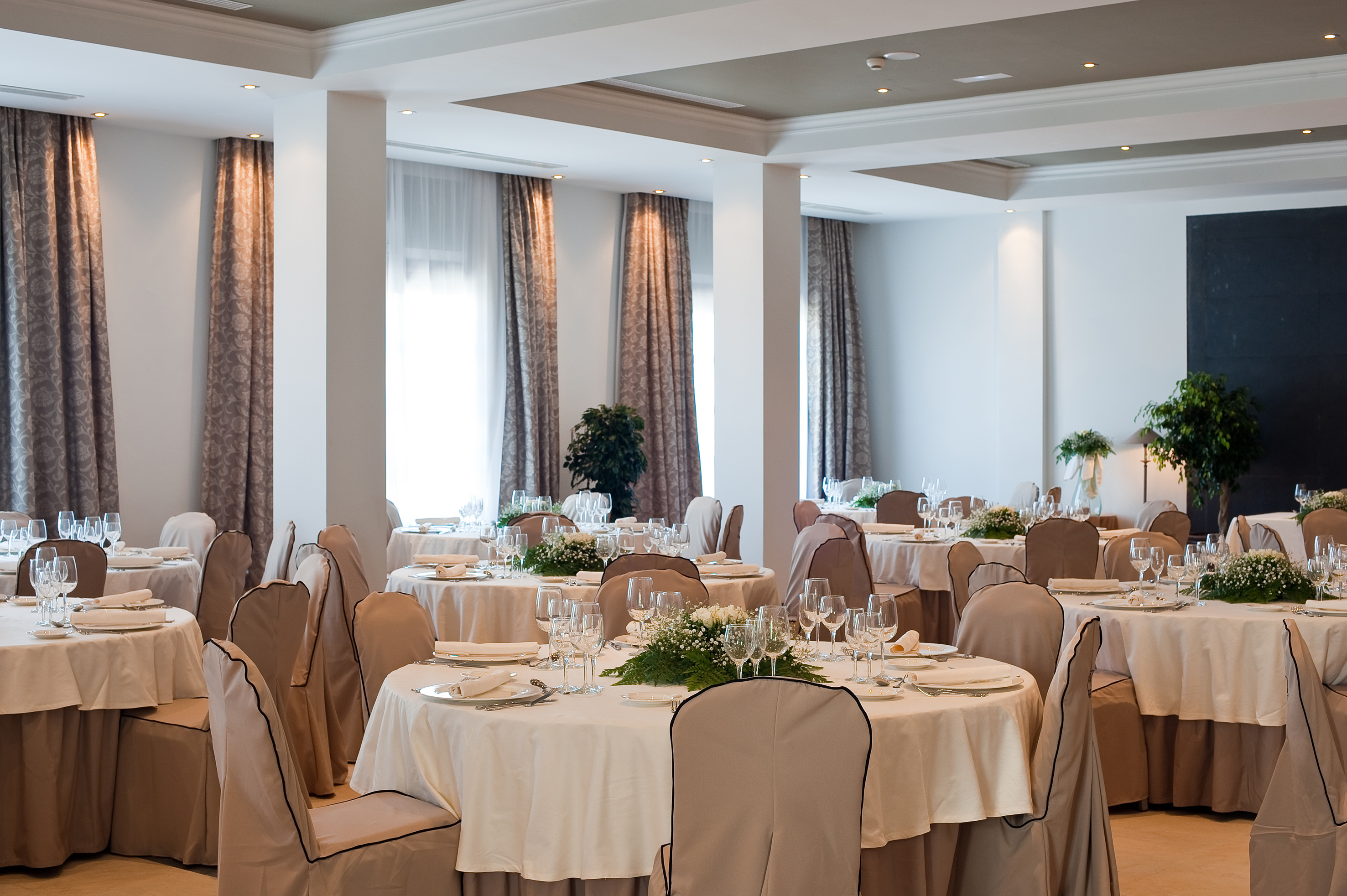 Elegant banquet room with set tables, white linens, and floral centerpieces.