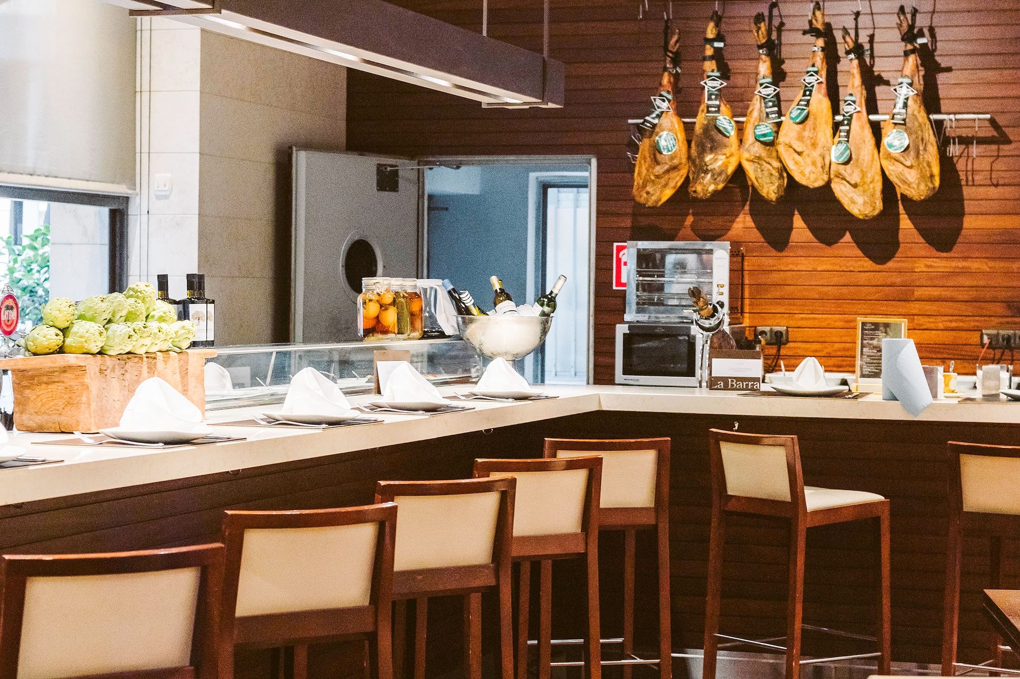 Spanish restaurant bar with hanging jamón legs and counter seating.