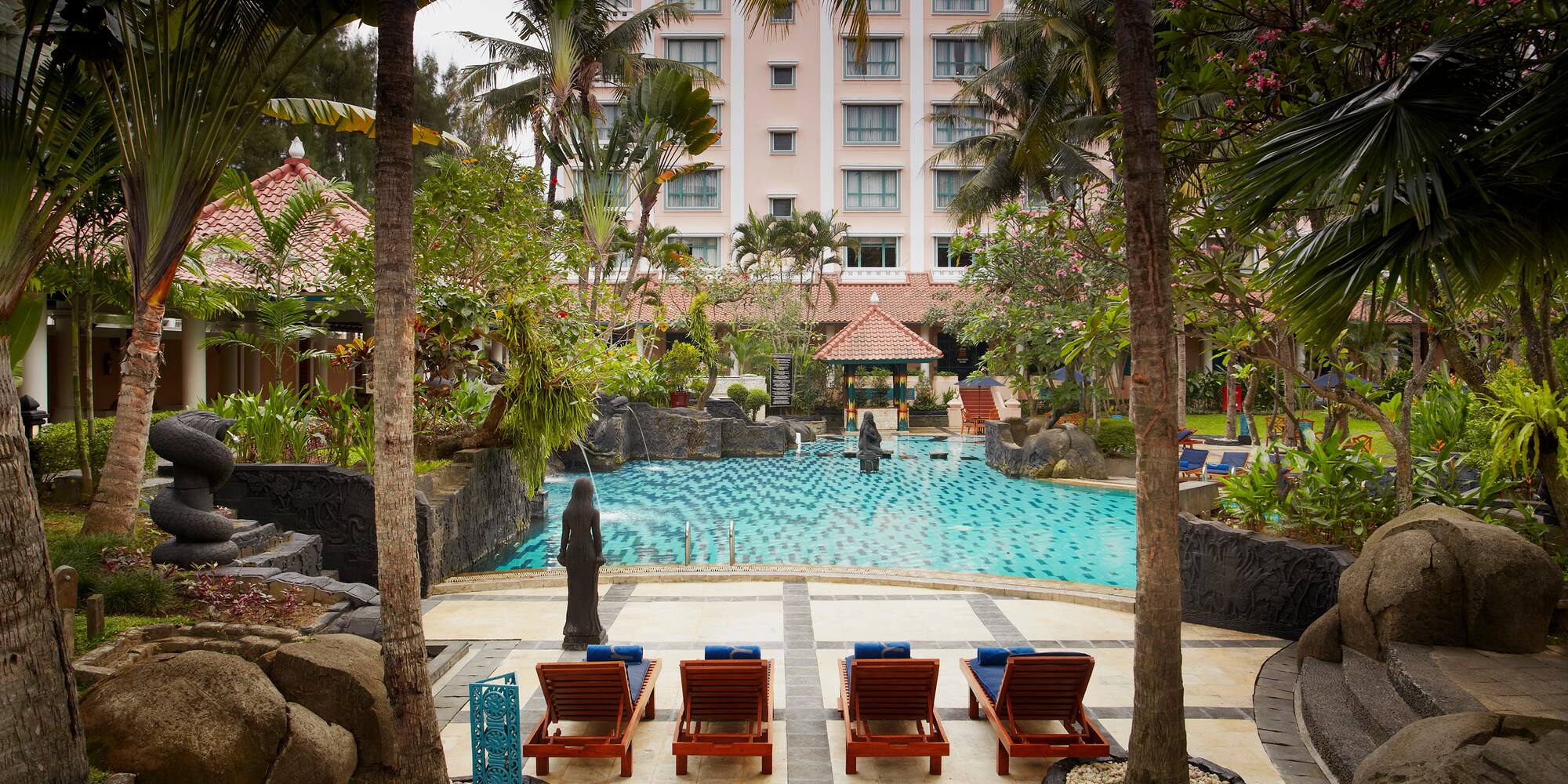 a pool with chairs and trees in front of a building