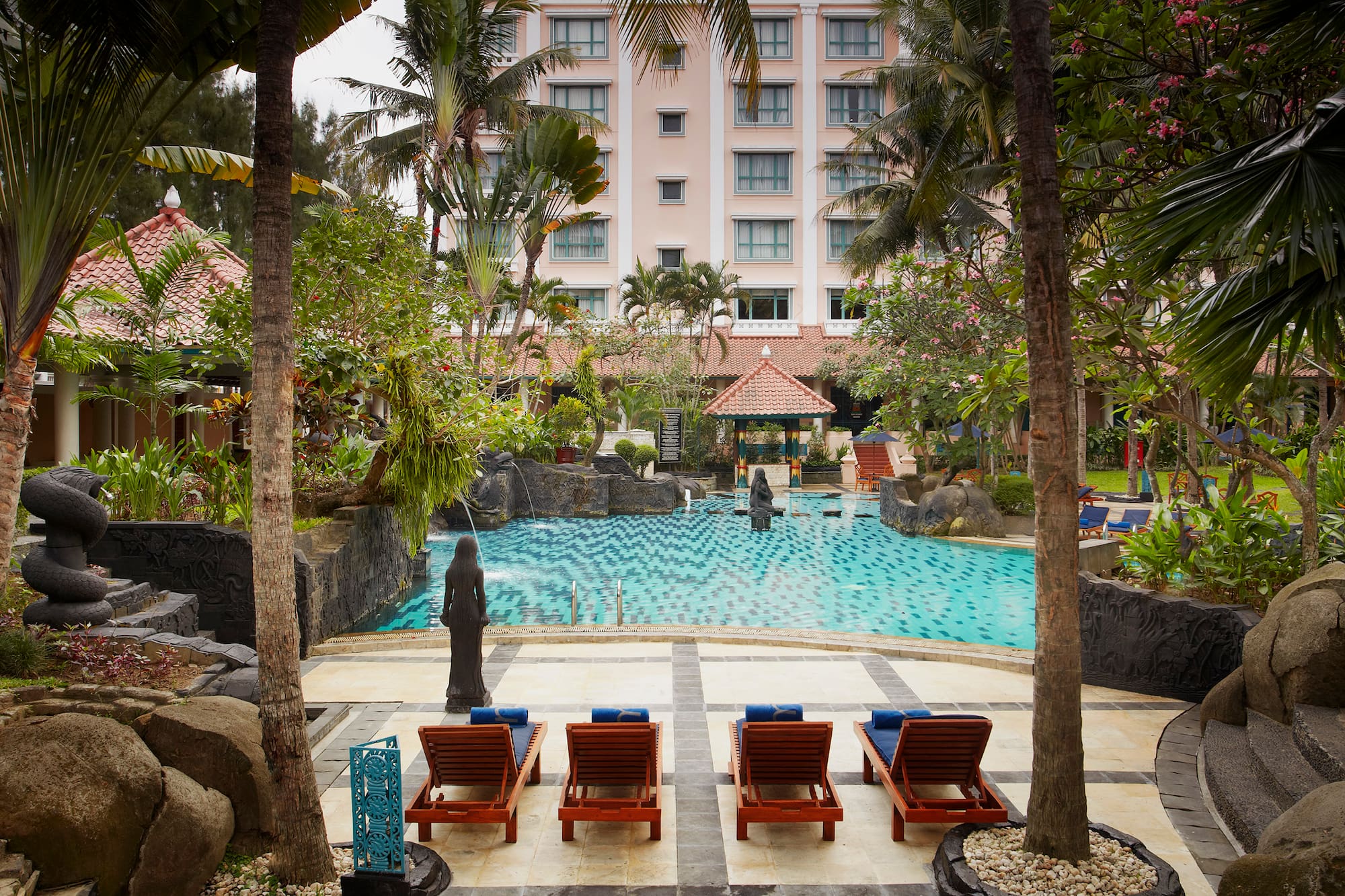 a pool with chairs and trees in front of a building