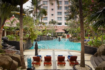 a pool with chairs and trees in front of a building
