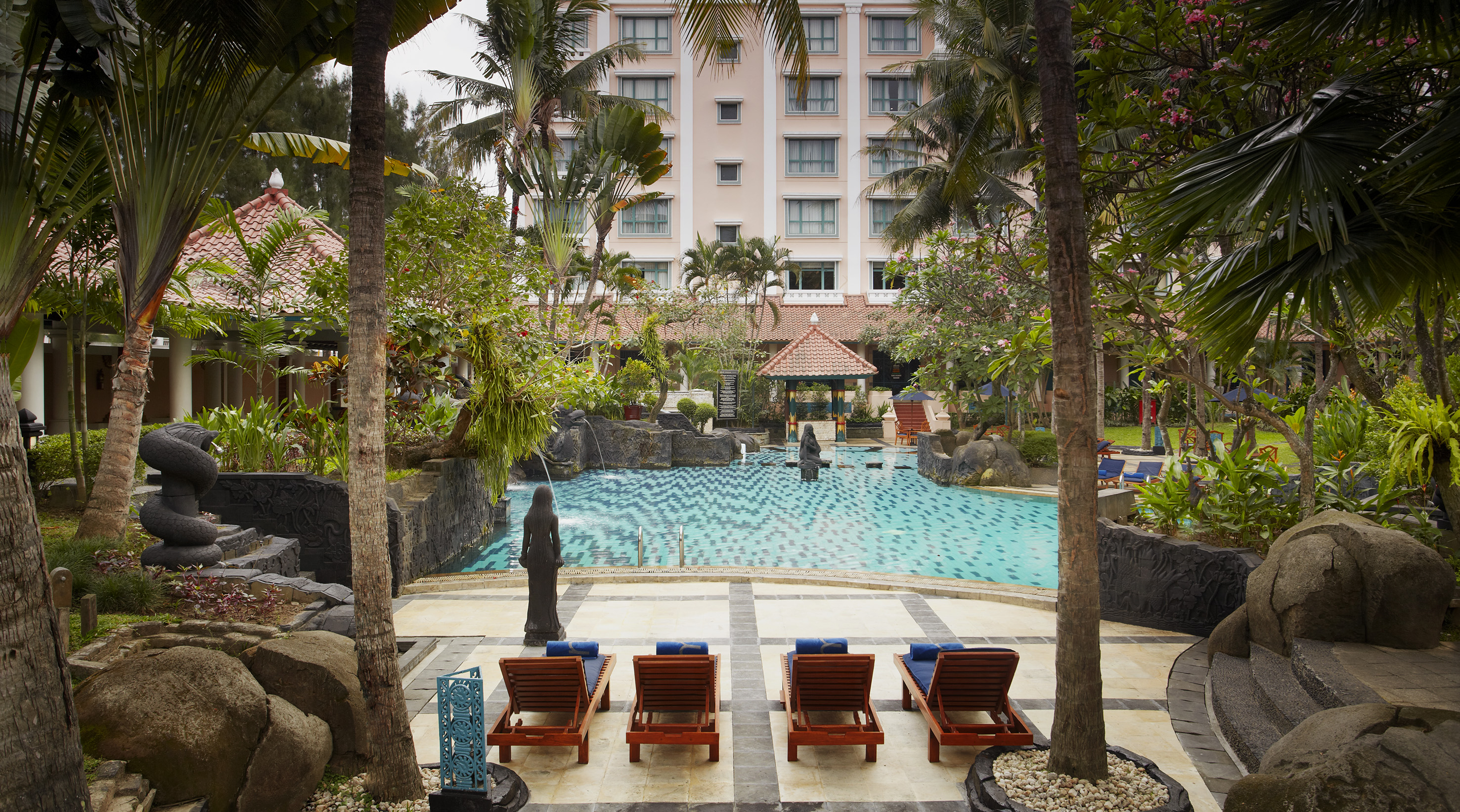 a pool with chairs and trees in front of a building