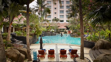 a pool with chairs and trees in front of a building