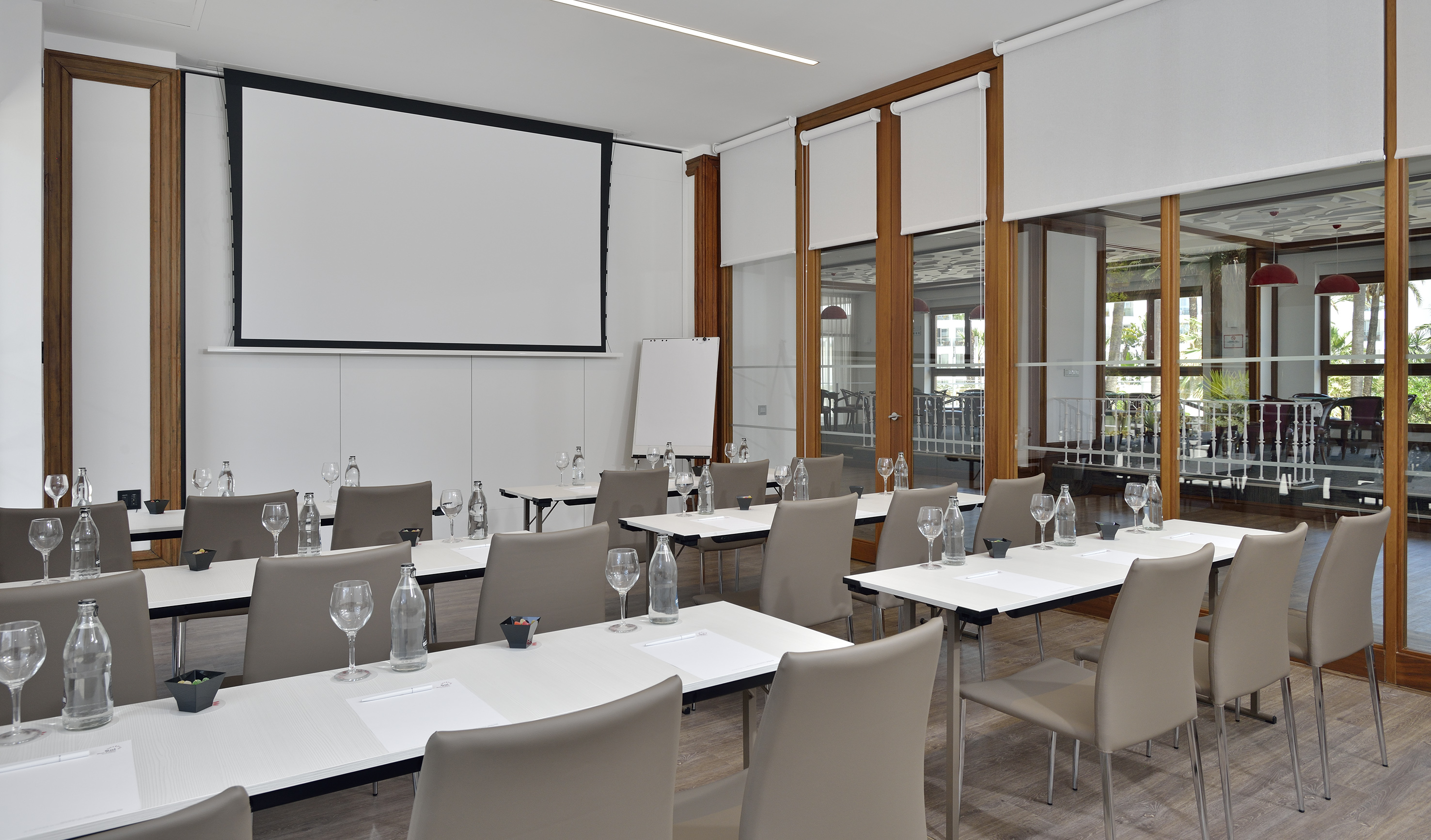 Modern conference room with projection screen, tables, chairs, and glass partition.