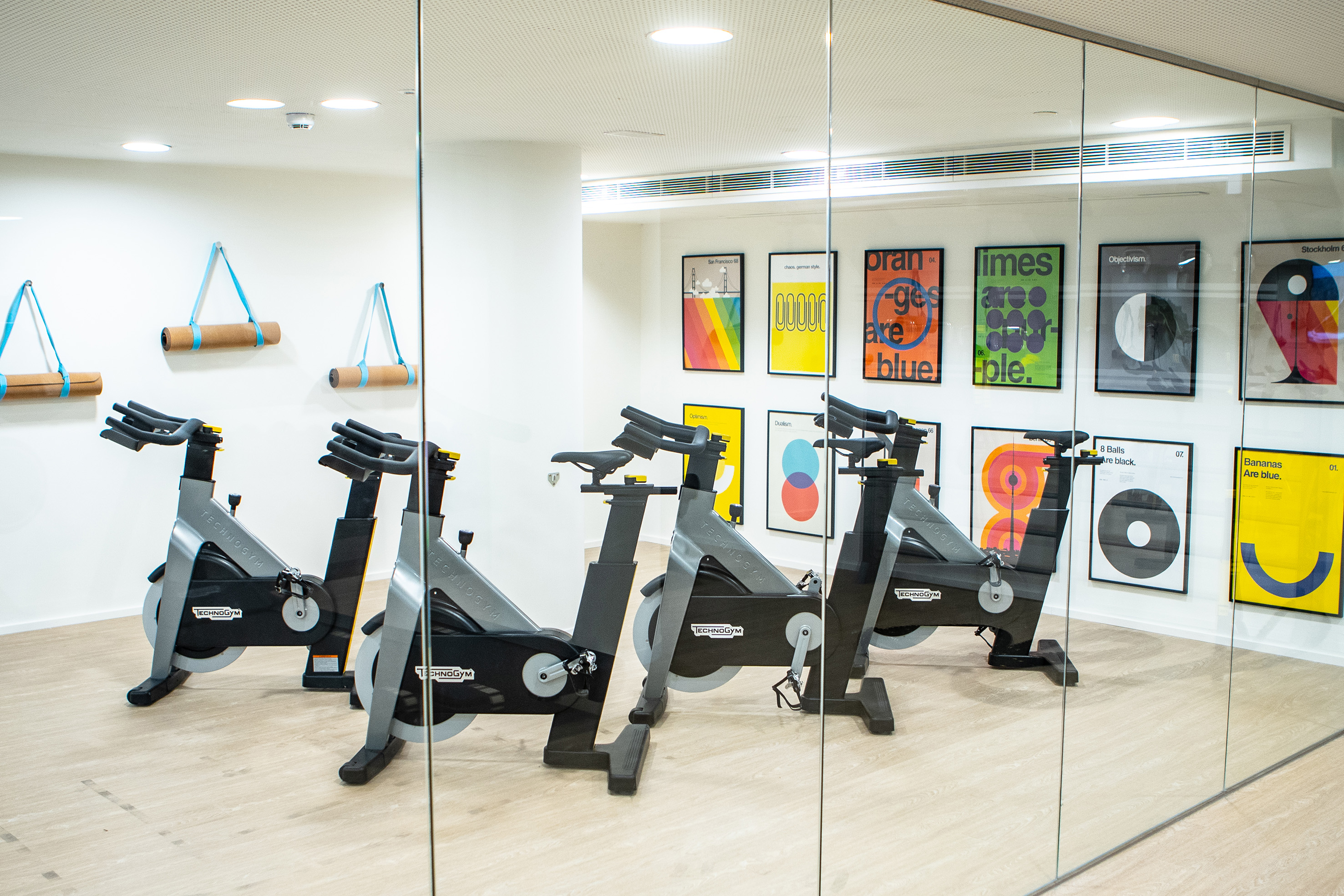 Technogym spin bikes, yoga mats, and colorful art in a modern fitness studio.