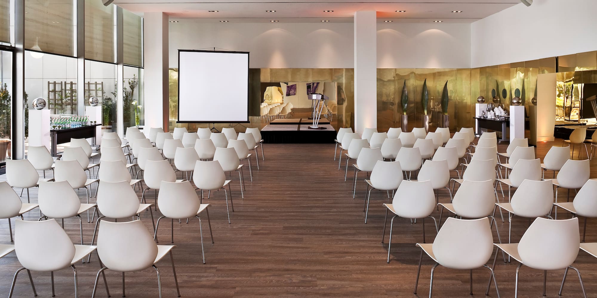 a room with white chairs and a screen