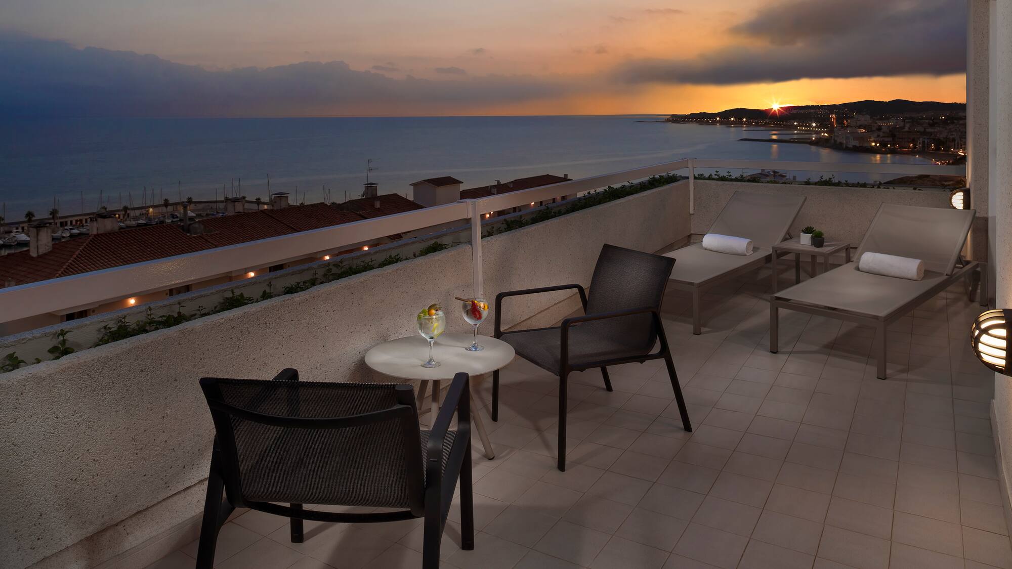 a patio with chairs and a table on a rooftop overlooking the ocean