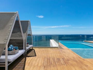 a deck with a pool and a deck with a bench and a view of the ocean