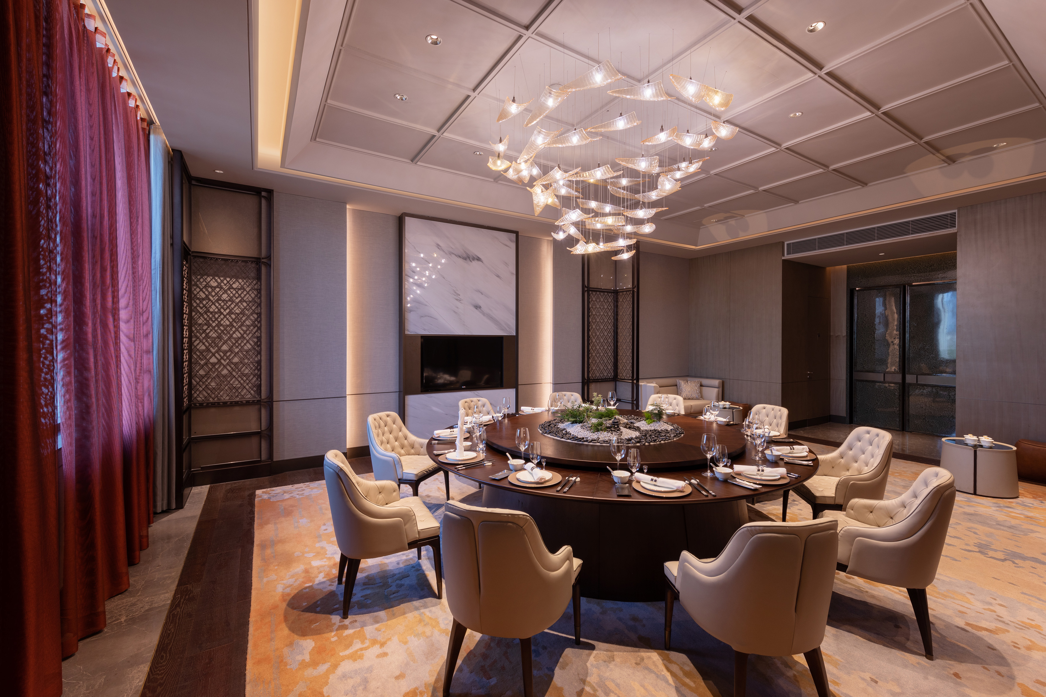 Elegant private dining room with round table, modern chandelier, and luxurious decor.