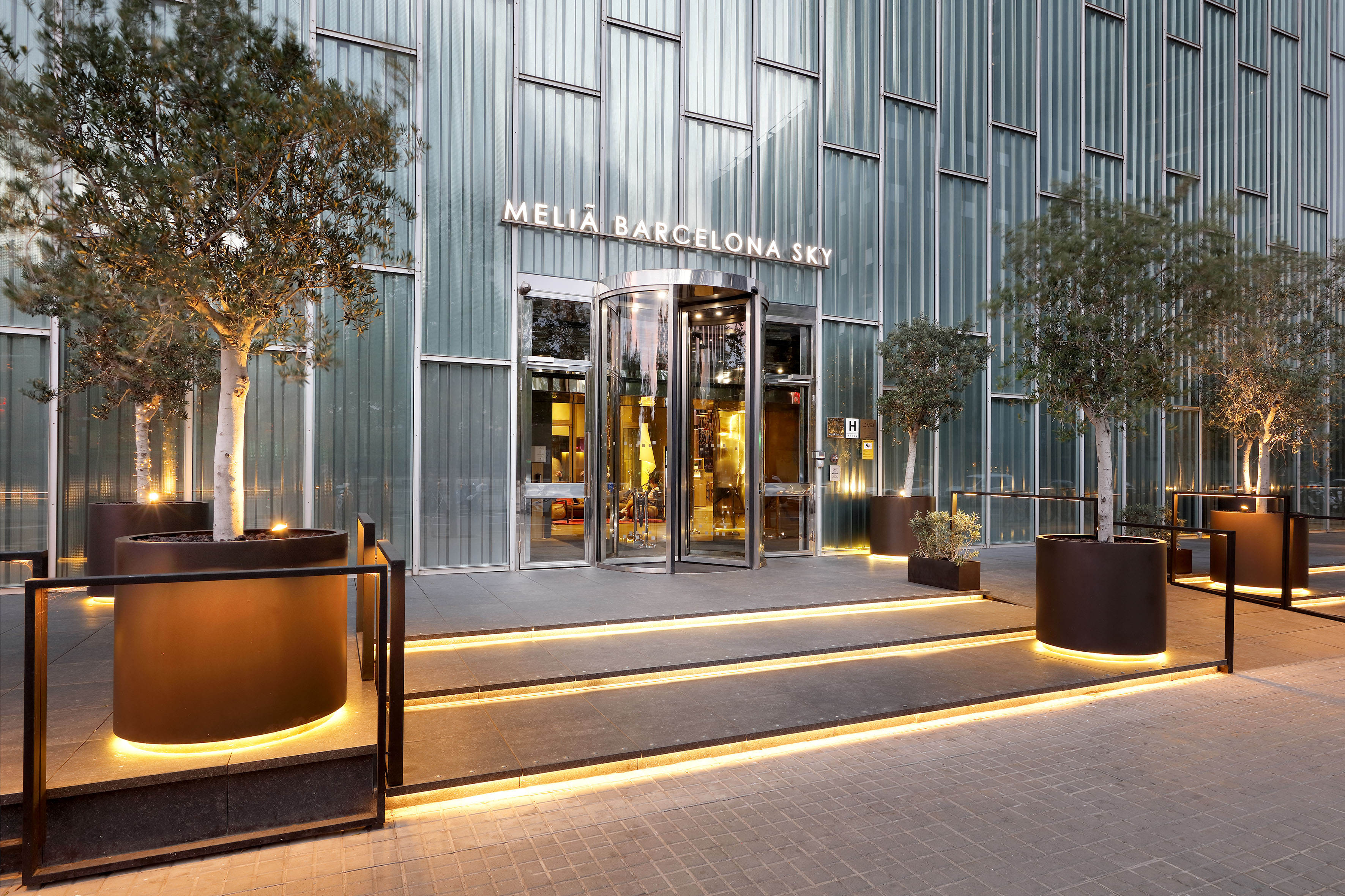 Melia Barcelona Sky hotel entrance with illuminated steps and modern glass facade.