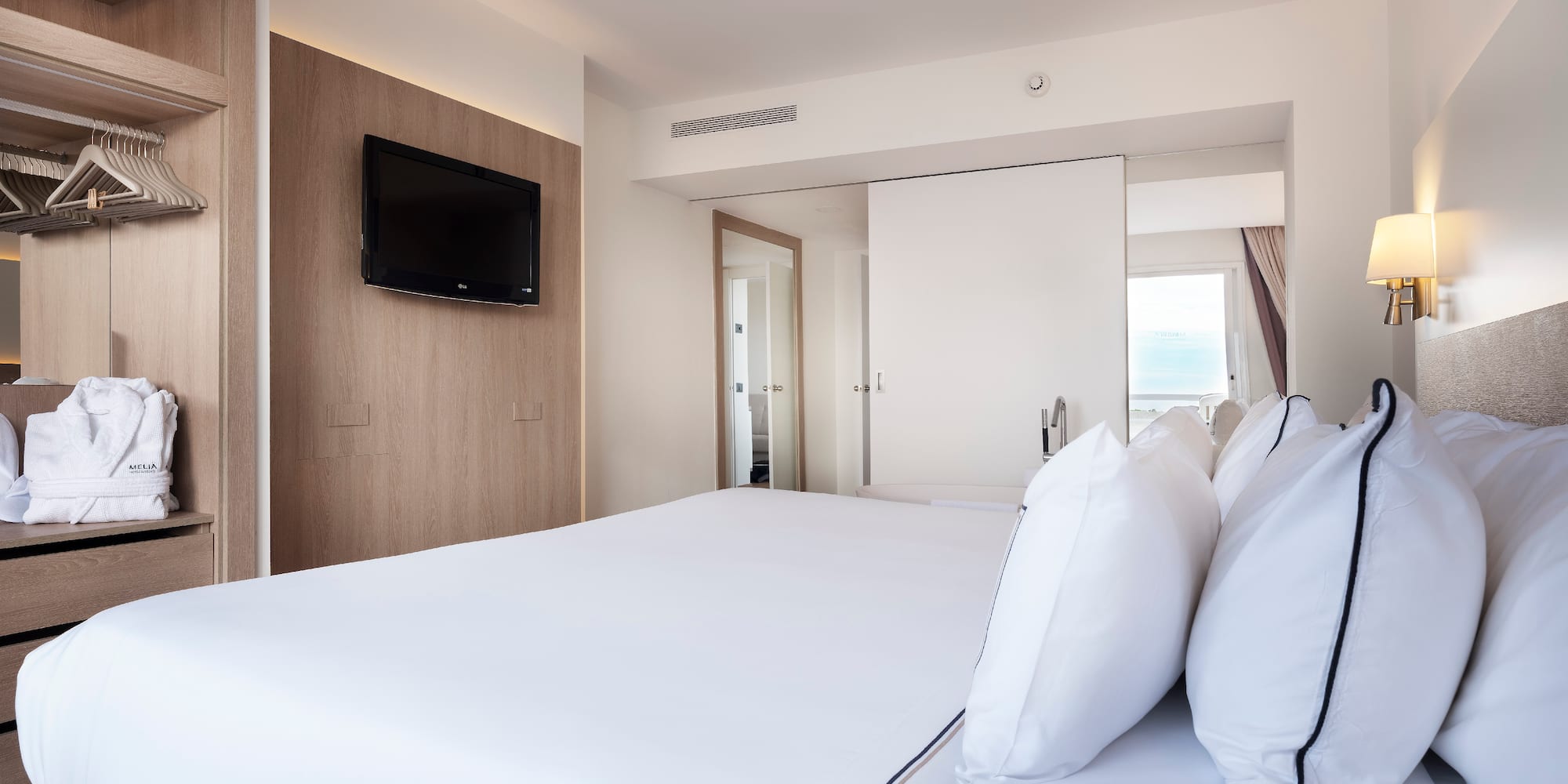 a bed with white sheets and a television on the wall