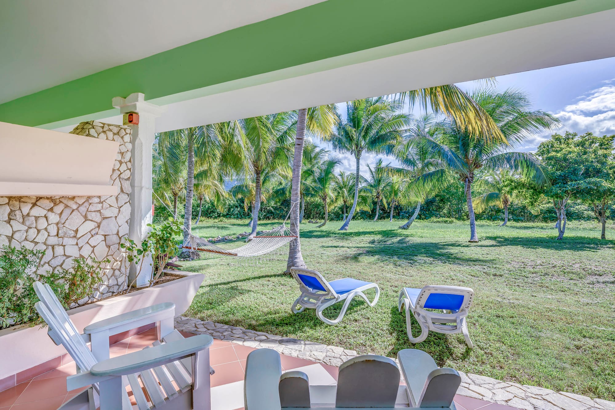 a patio with chairs and hammocks in a tropical garden