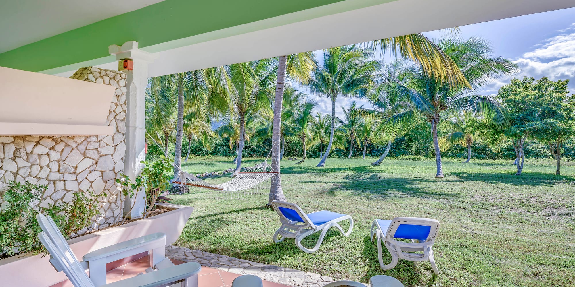 a patio with chairs and hammocks in a tropical garden