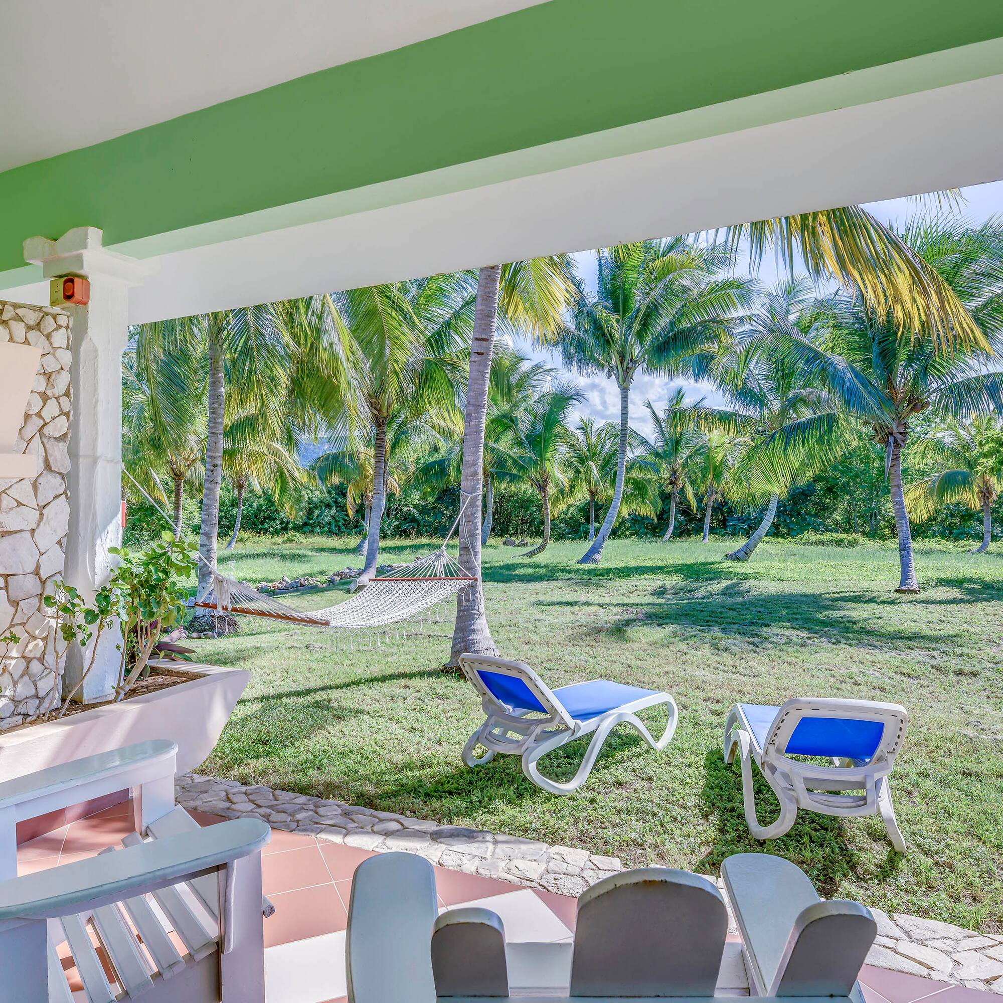 a patio with chairs and hammocks in a tropical garden