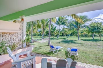 a patio with chairs and hammocks in a tropical garden