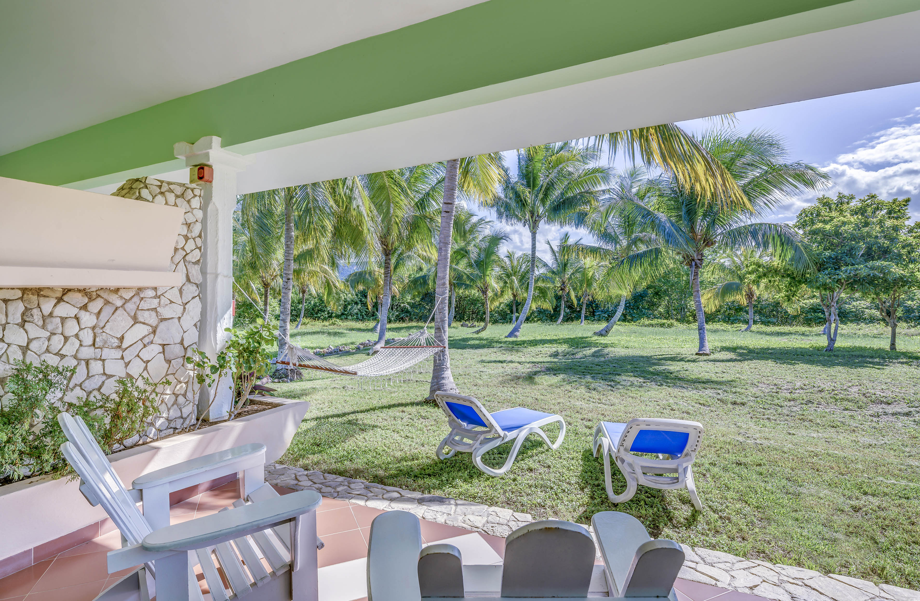 a patio with chairs and hammocks in a tropical garden