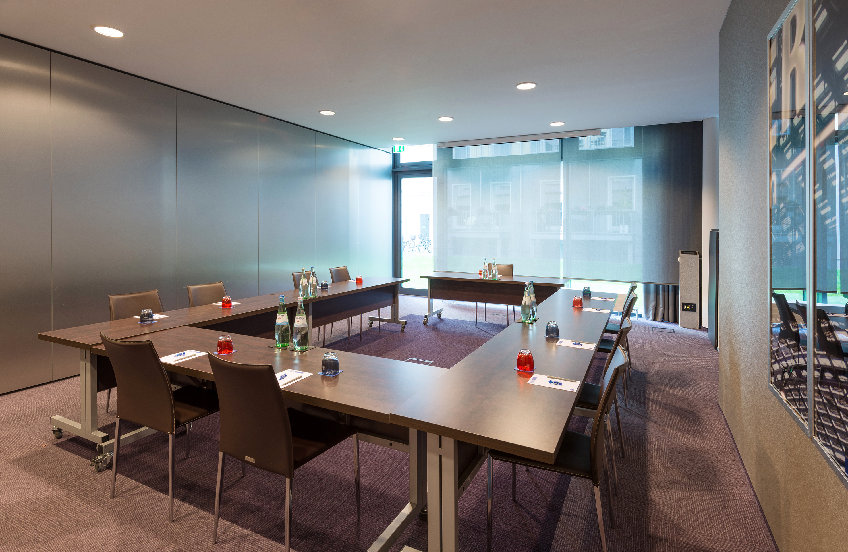 Sleek U-shape conference room with tables, chairs, and natural light from windows.