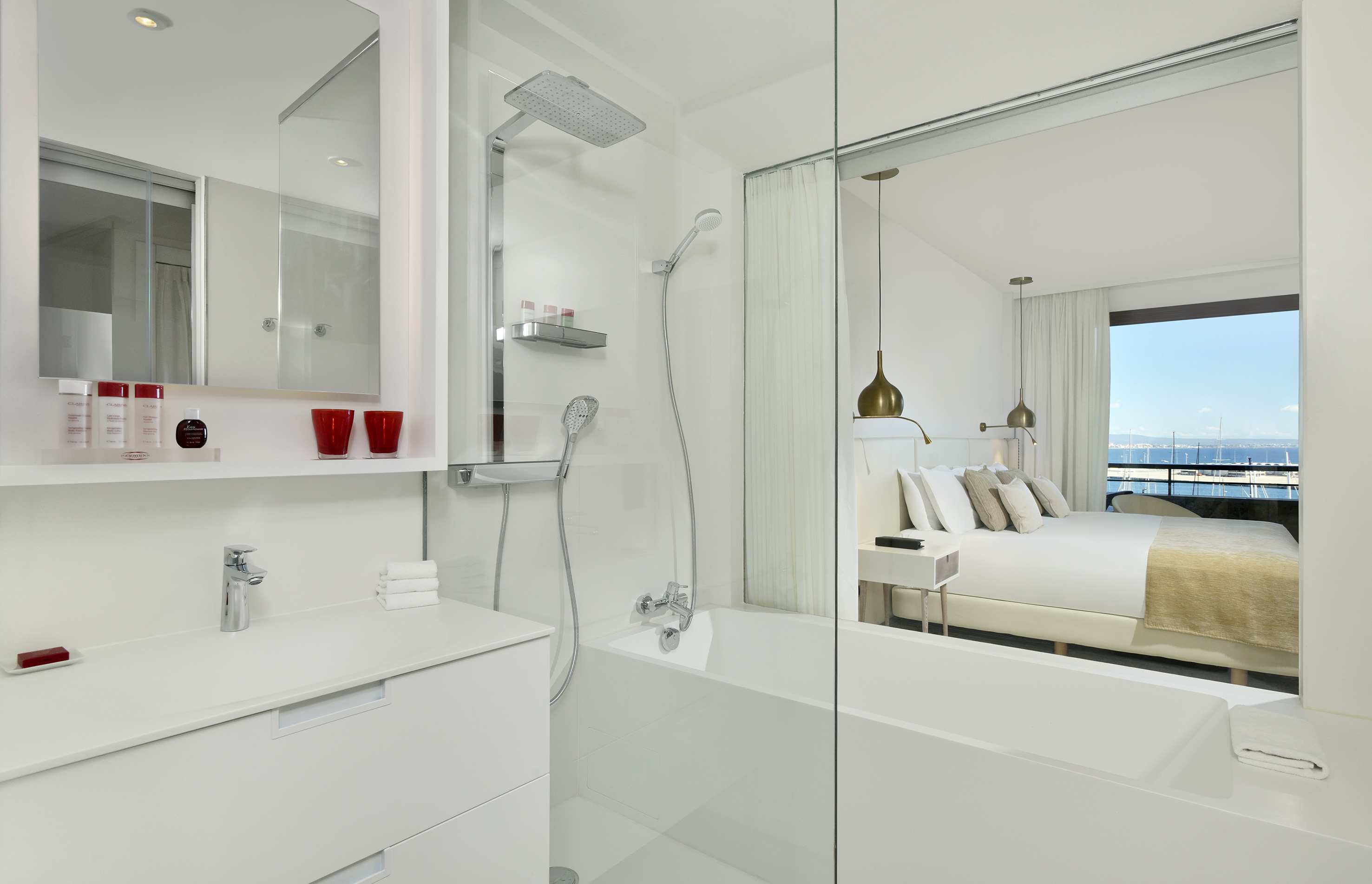 Modern hotel bathroom and bedroom suite with sea view over marina.