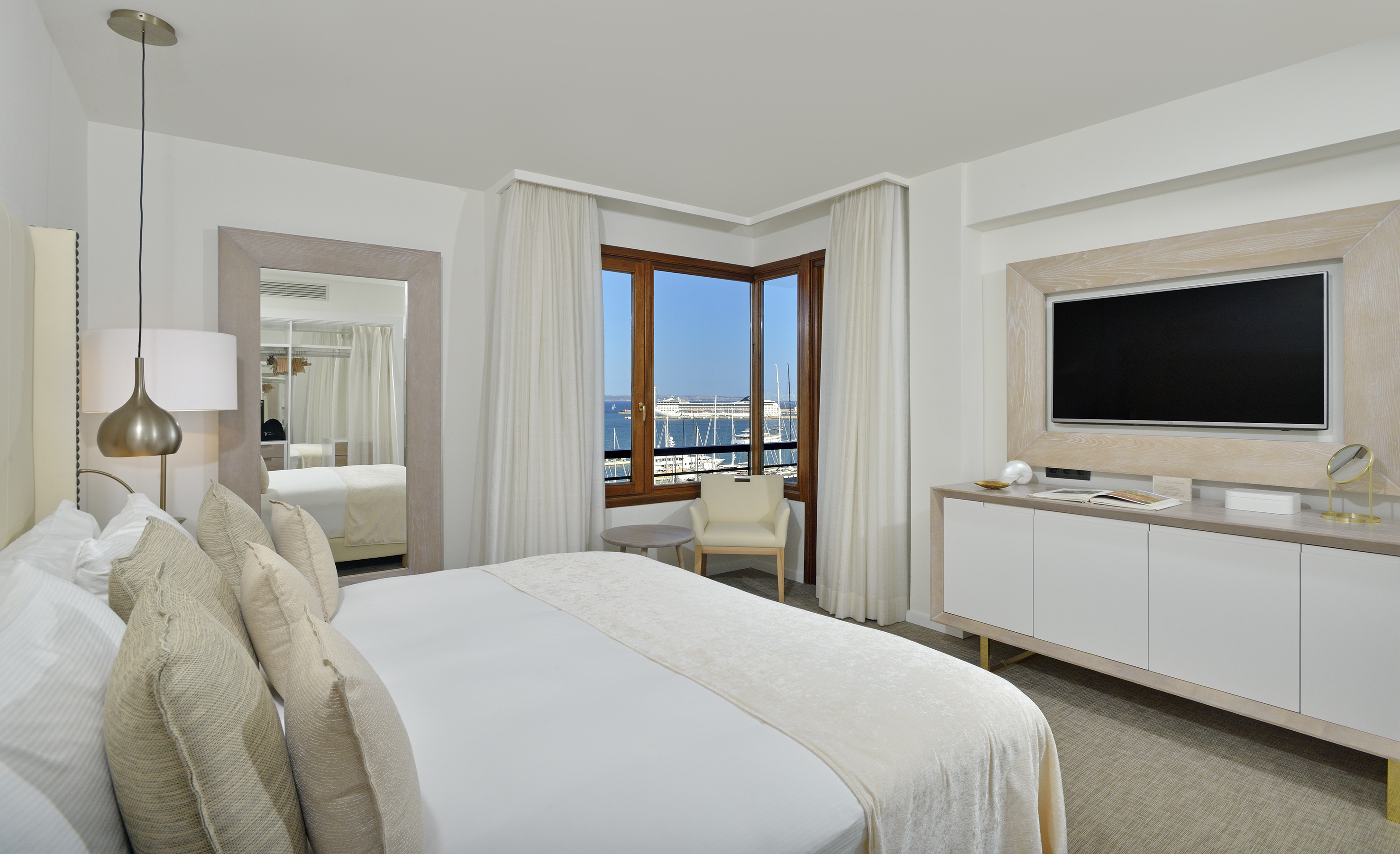 Modern hotel bedroom with panoramic marina view and elegant decor.
