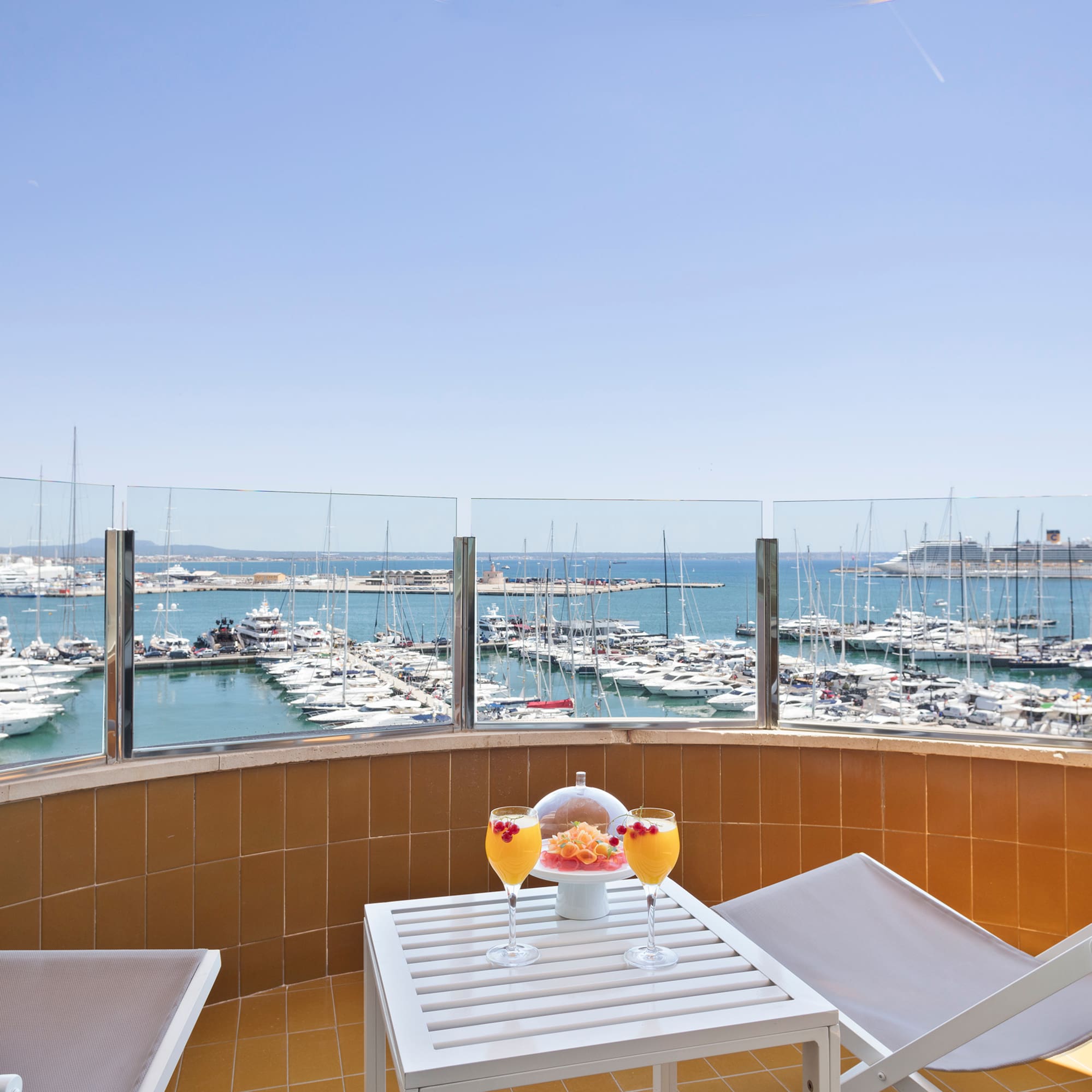 a table with drinks and chairs on a balcony overlooking a body of water