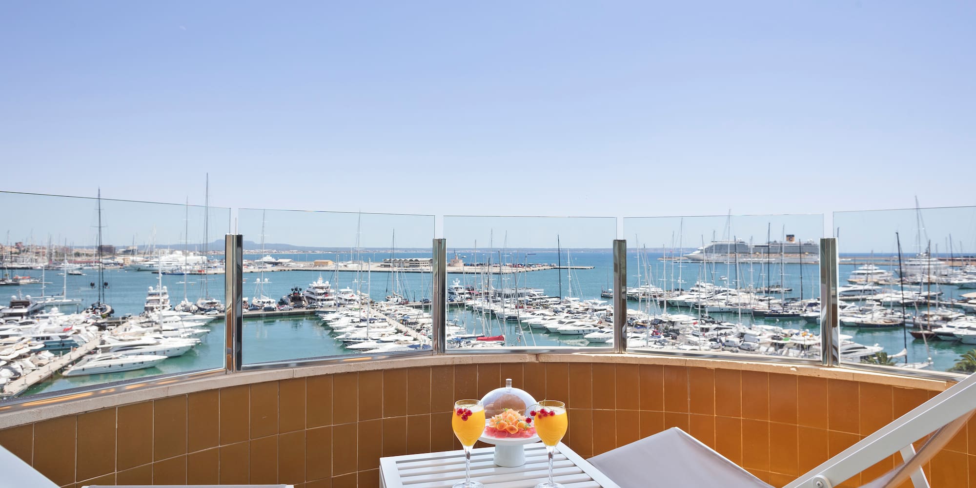 a table with drinks and chairs on a balcony overlooking a body of water