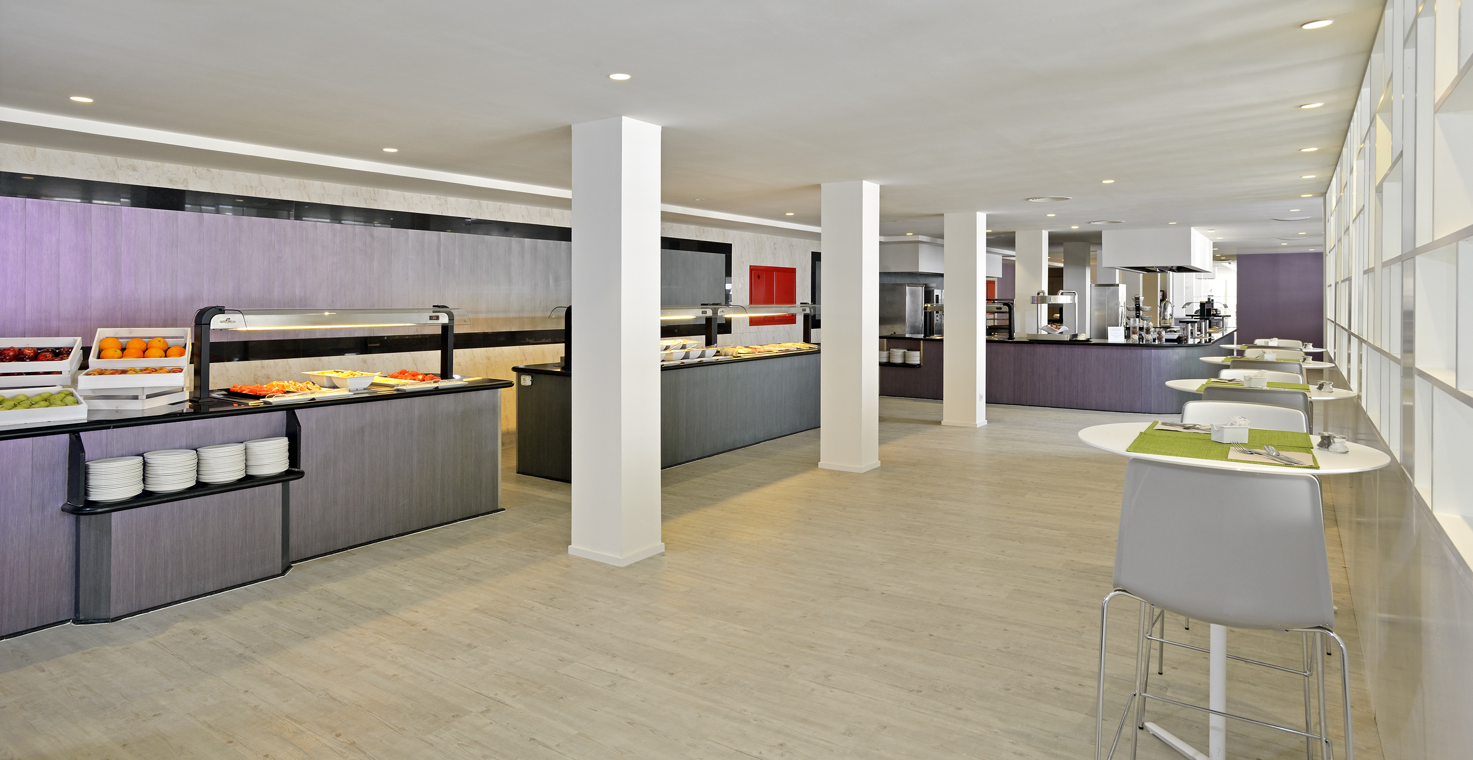 Bright, modern buffet restaurant with food stations, fruit, and dining tables.