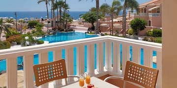 a table and chairs on a balcony overlooking a pool and water